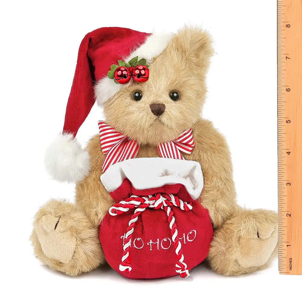 Christmas teddy bear with red sack, Santa hat, and candy cane details on a white background.