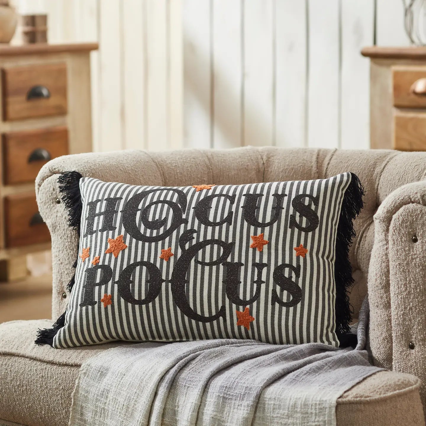 Decorative pillow with 'HOCUS POCUS' text on a couch in a home setting