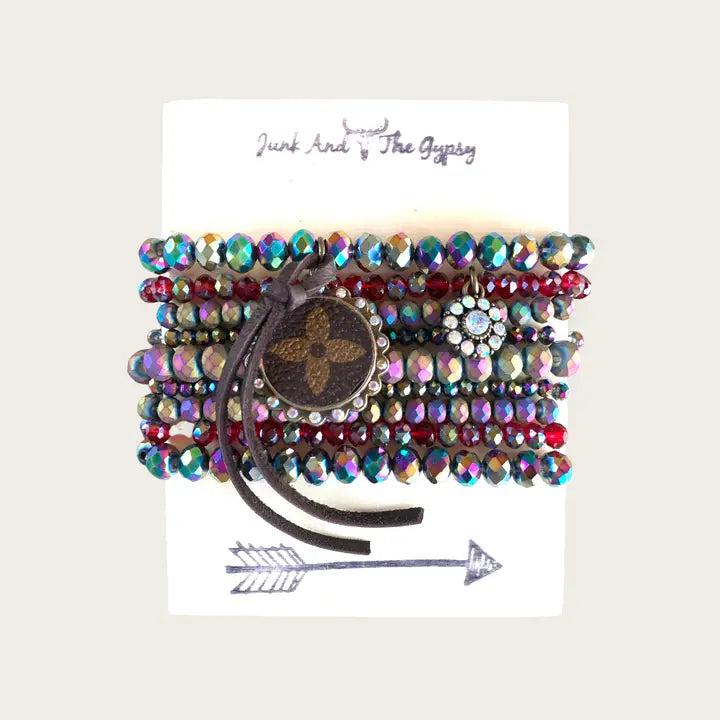 Multicolored beaded bracelet with wooden accent on a white card with 'Junk and the Gypsy' branding.