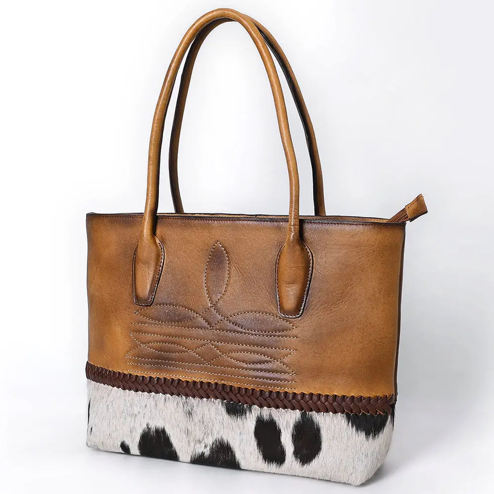 Brown leather handbag with cowhide pattern on a white background