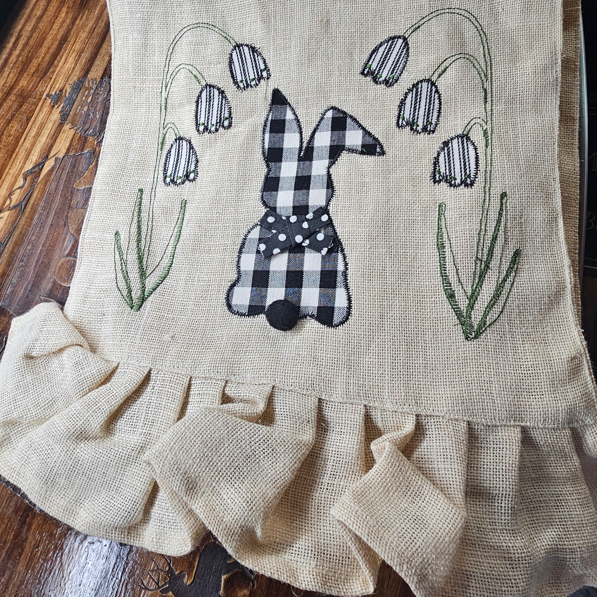 Embroidered towel with a checkered bunny and floral design on a wooden surface