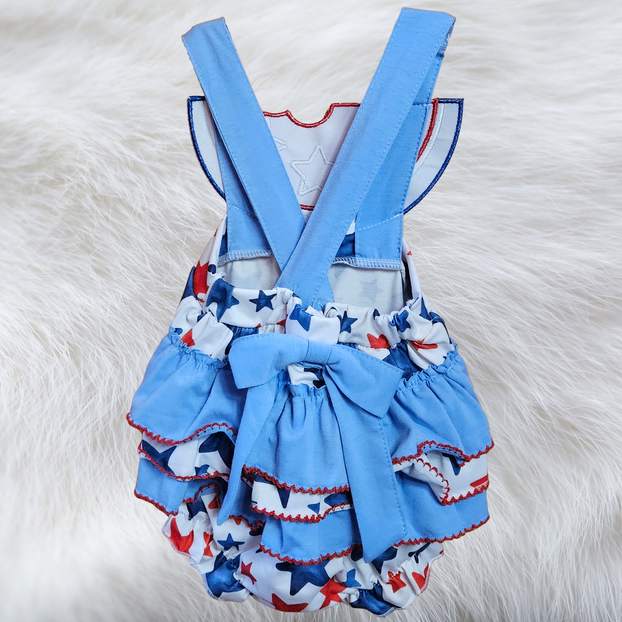 Children's blue romper with star pattern and suspenders on a white fur background