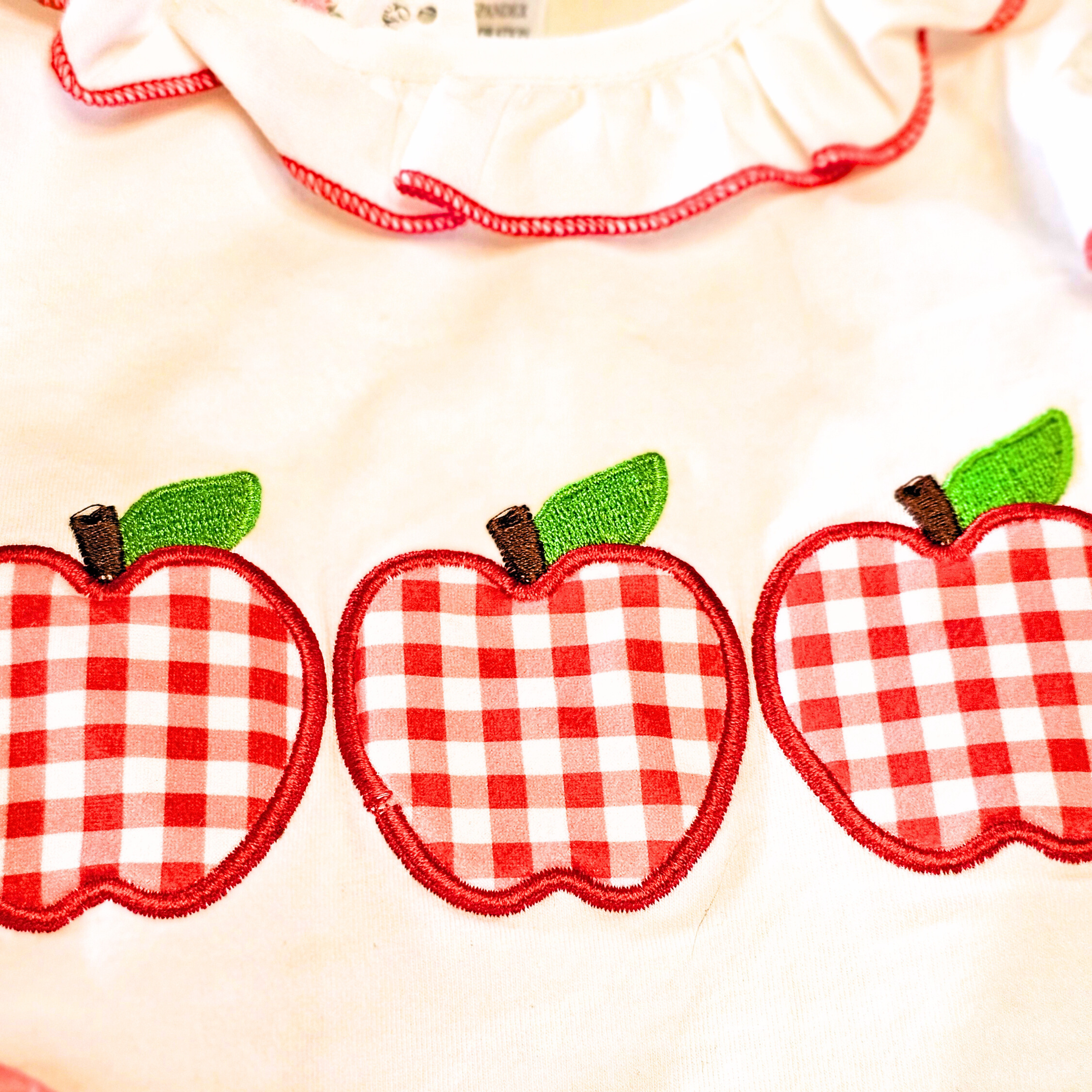 Red and white checkered apples with green leaves on a white background