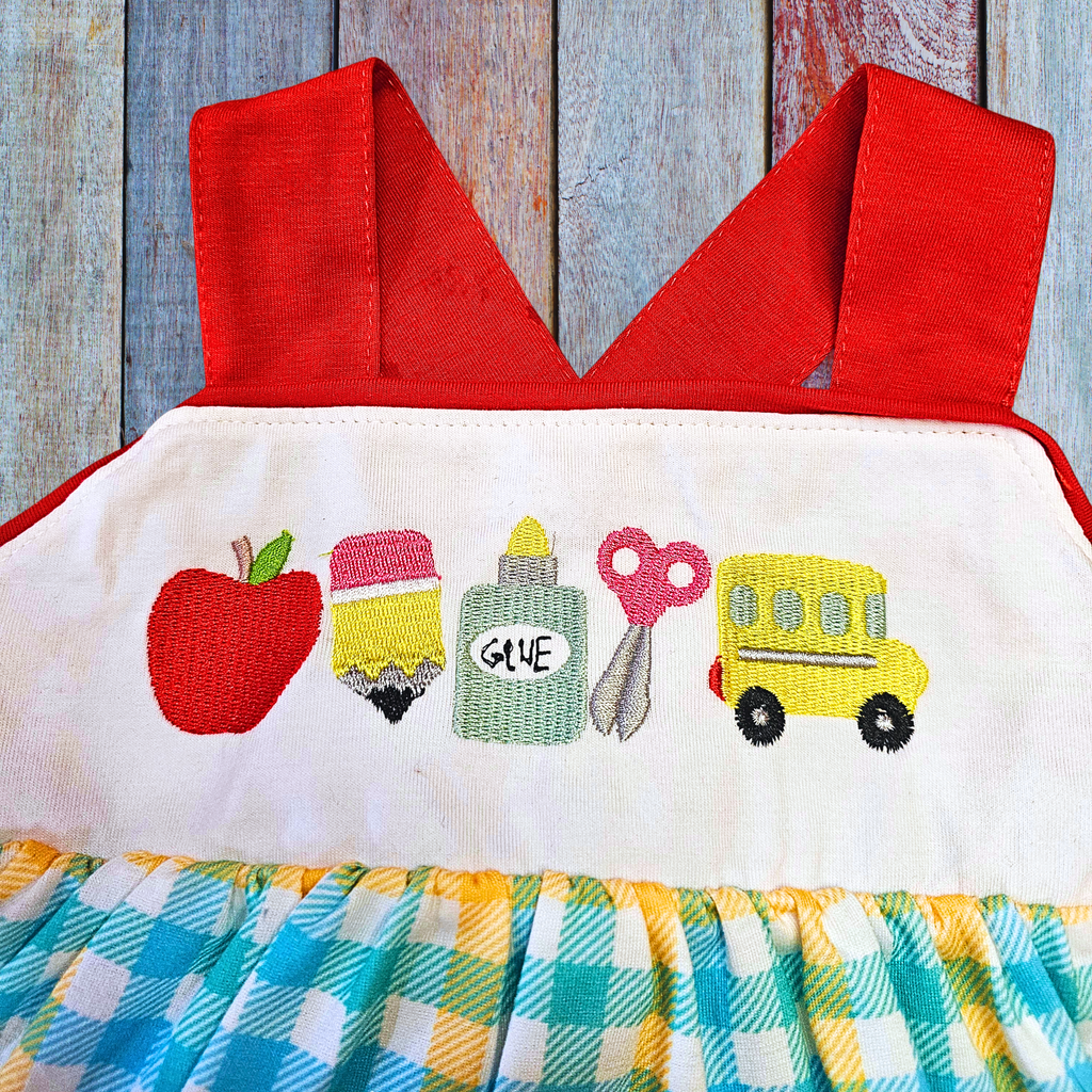 Children's dress with red top and colorful bottom on a wooden background