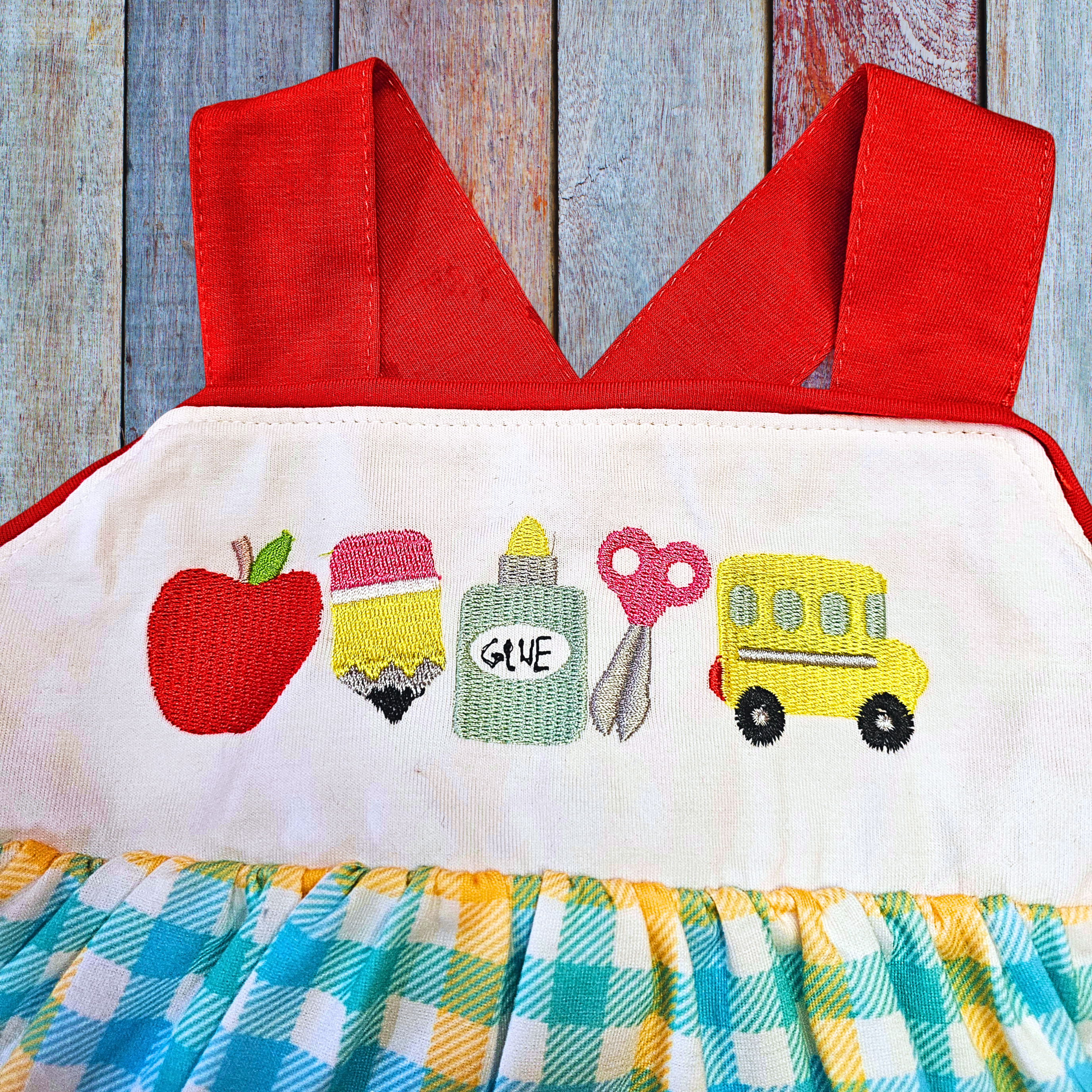 Children's dress with red top and colorful bottom on a wooden background