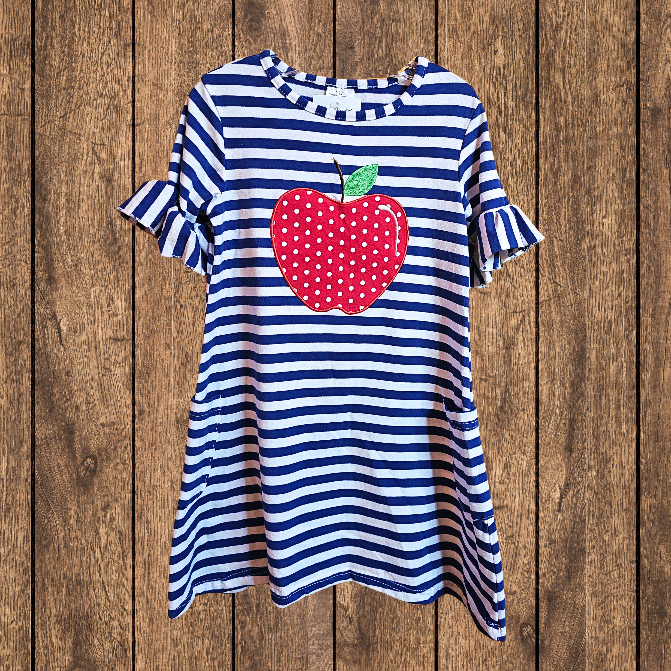 Blue and white striped dress with a red apple design on a wooden background