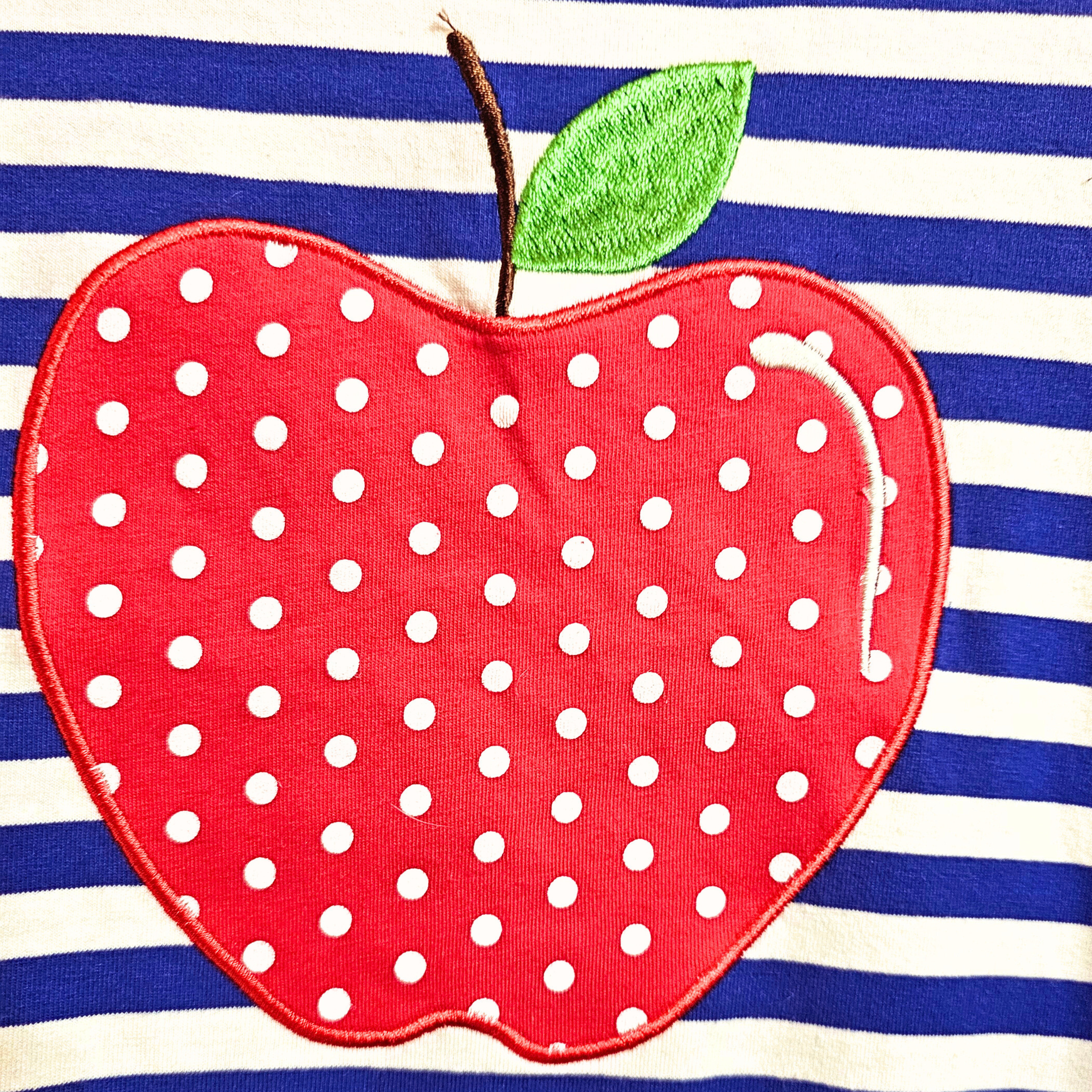 Red polka dot apple patch on a blue and white striped background