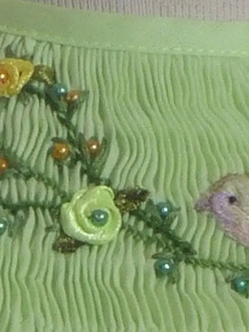 Embroidered fabric with floral patterns and a hedgehog on a green background