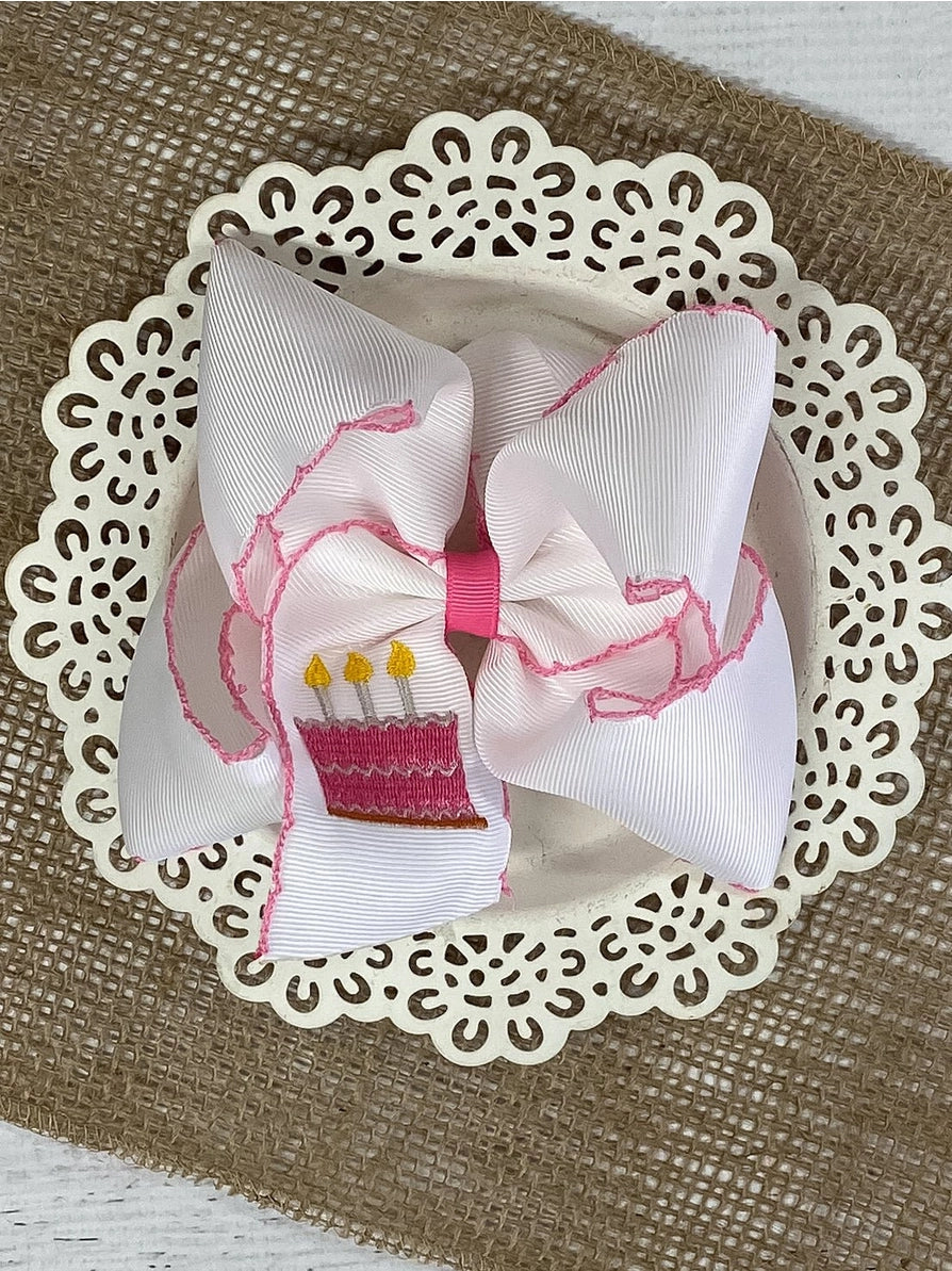 White bow with pink cake on a decorative doily