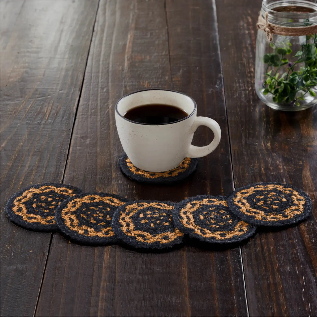 Set of black and gold coasters with a white mug on a wooden table.