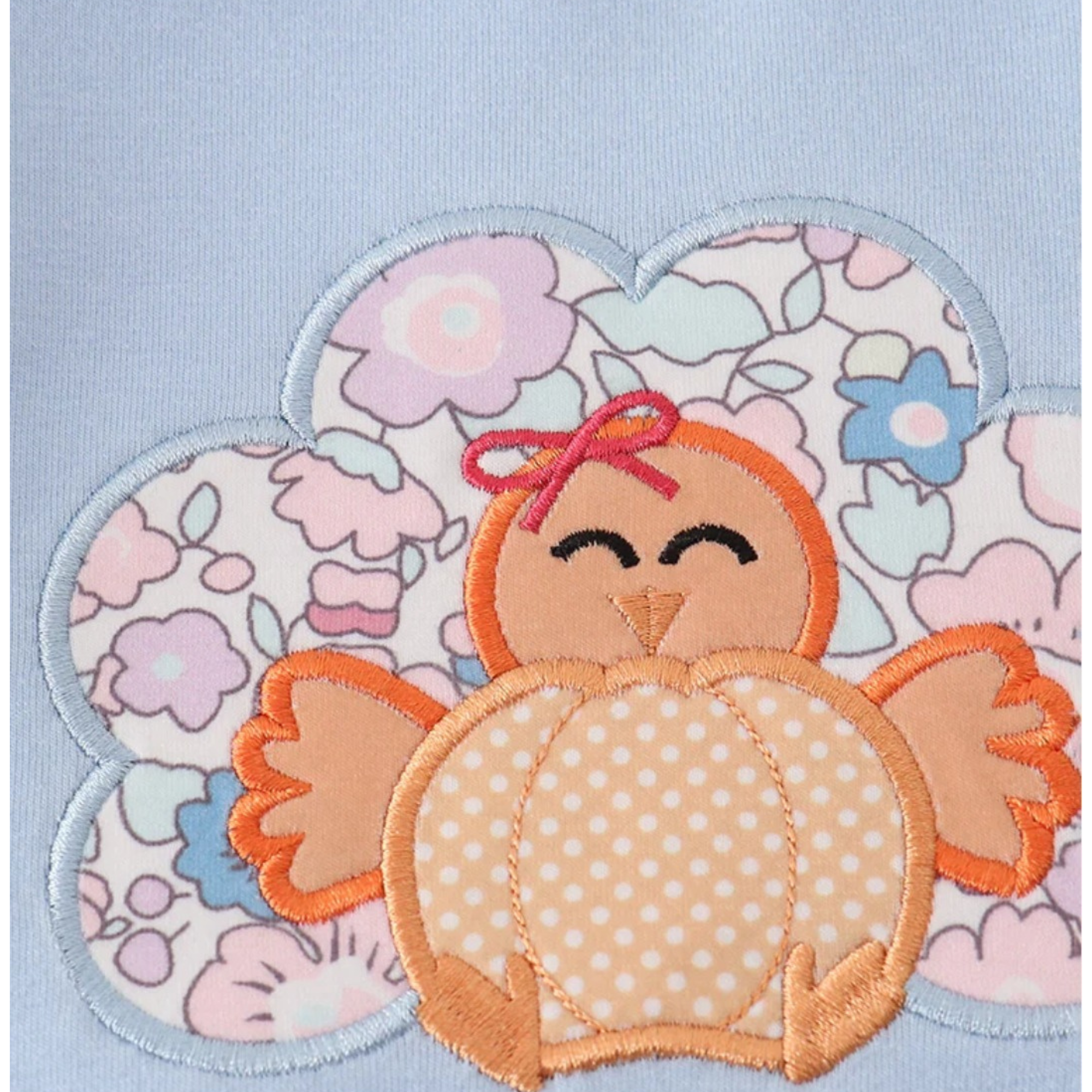 Embroidered patch of a cartoon owl with a bow on a floral background