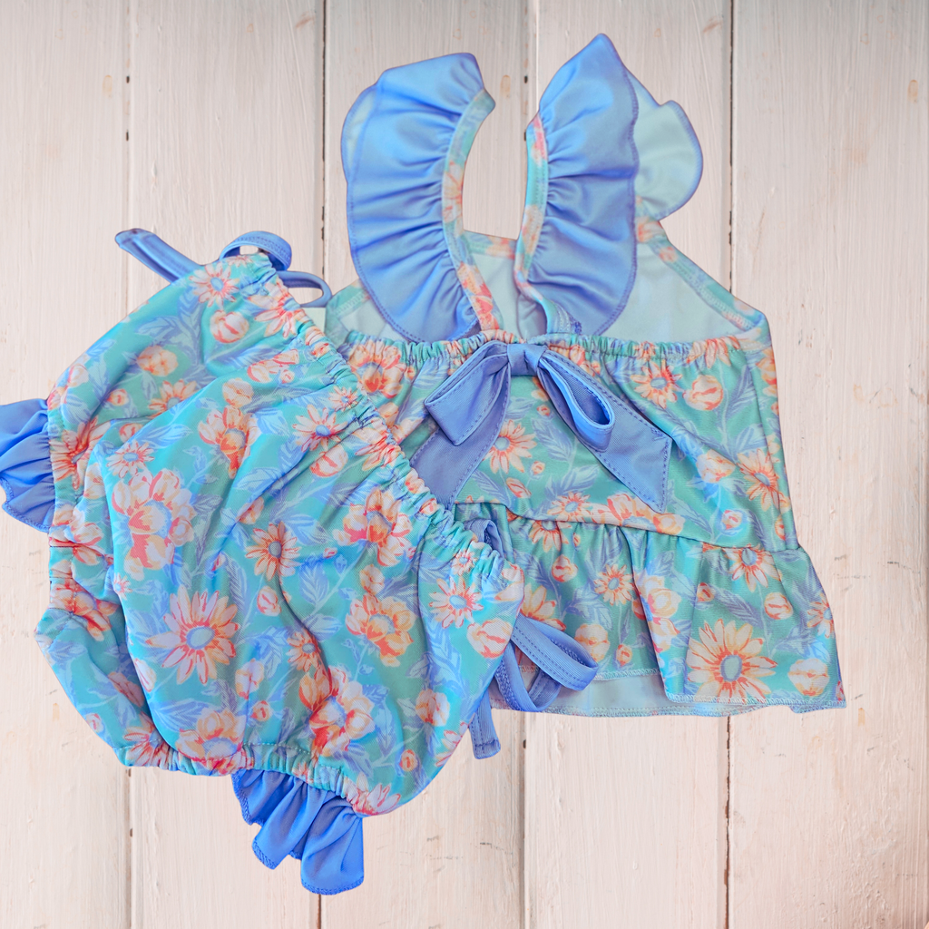Children's blue floral swimsuit with ruffled details on a wooden background