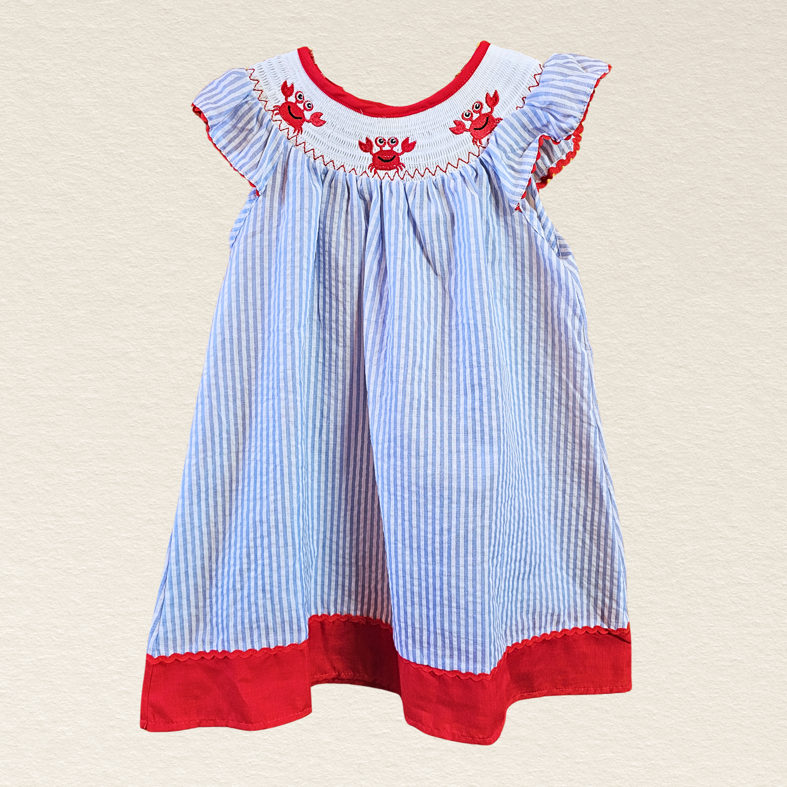Children's dress with blue and white striped pattern and red accents on a beige background