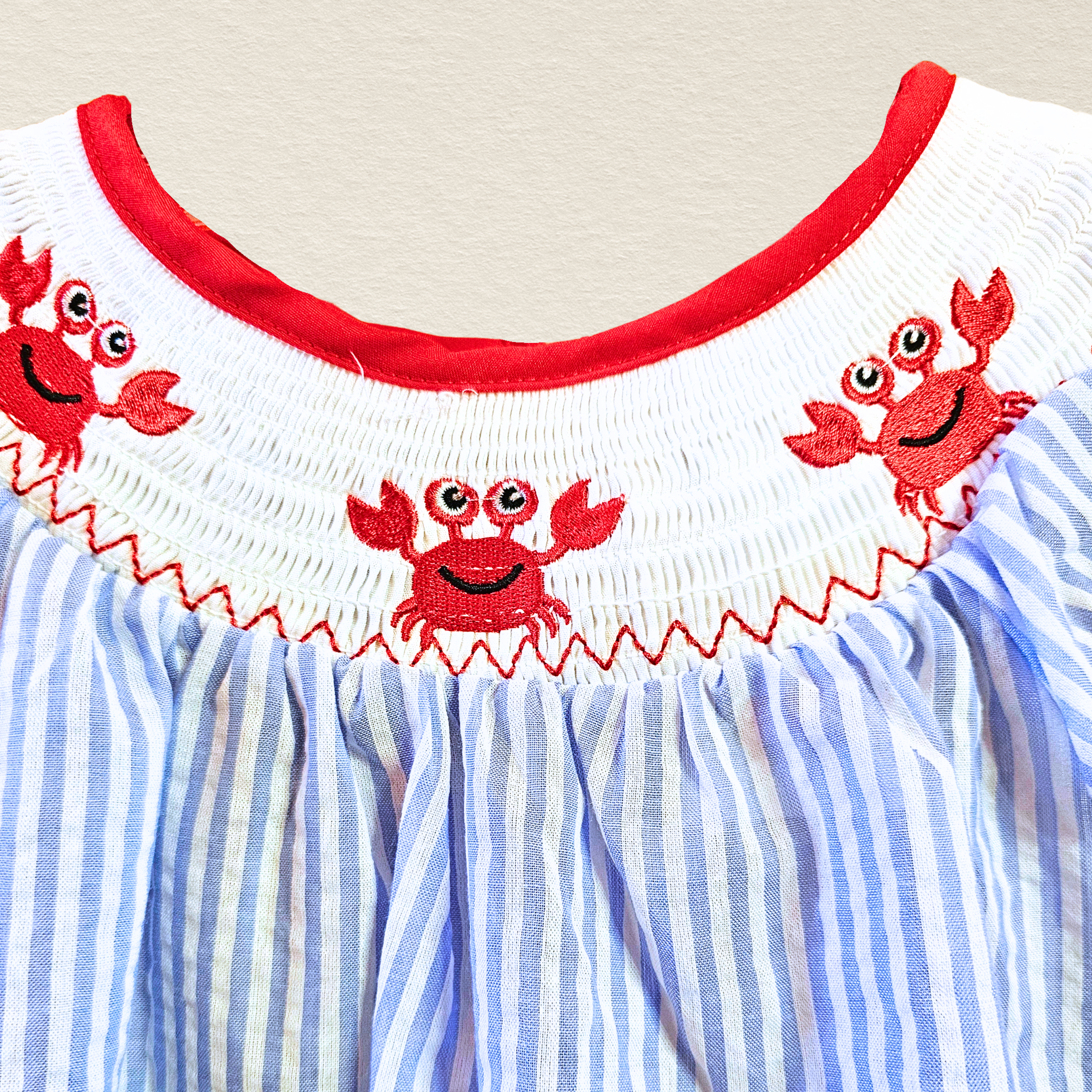 Children's dress with red crab embroidery on a white and blue striped background