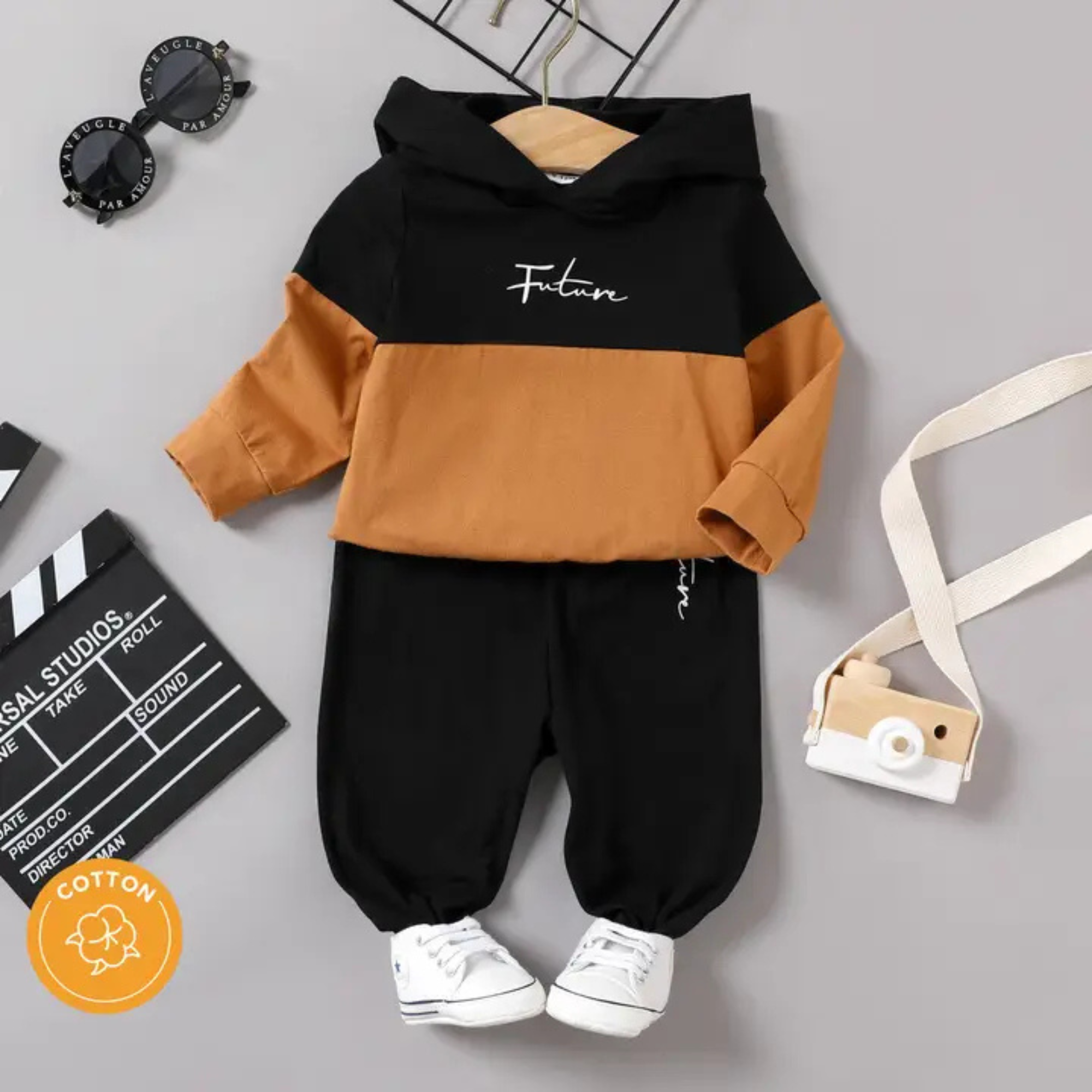 Children's outfit with black and brown hoodie and black pants on a gray background.