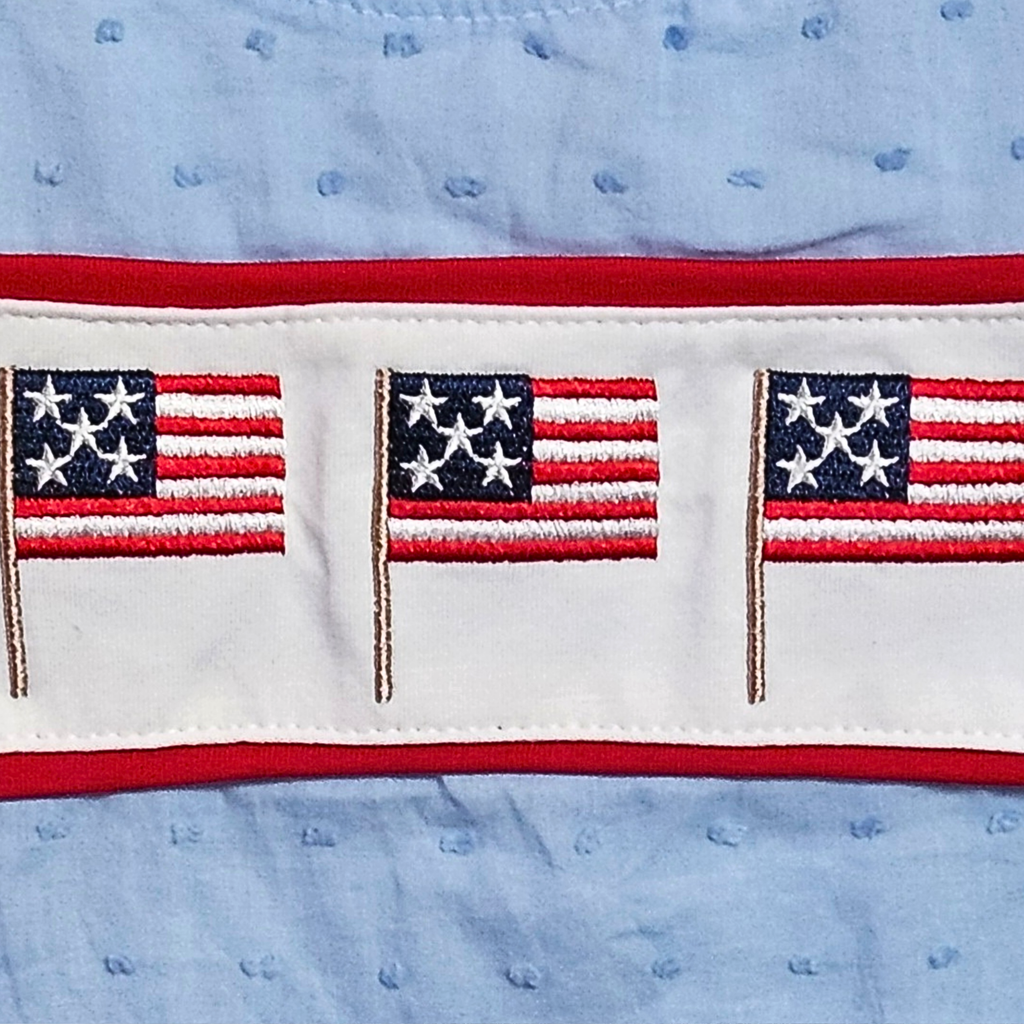 Three embroidered American flags on a fabric with a blue background