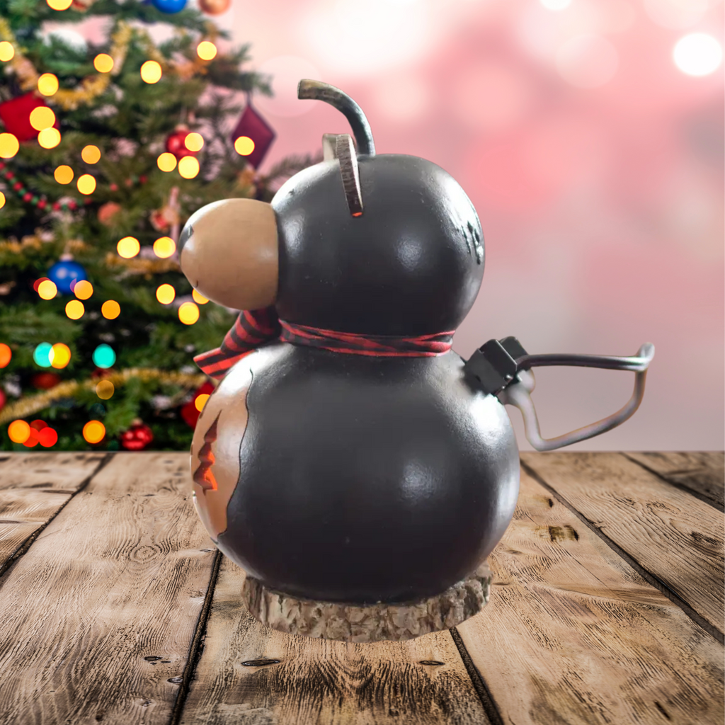 Decorative left side profile gourd shaped like a bear with a plaid ribbon and with a plug showing on a wooden surface with a blurred Christmas tree in the background.