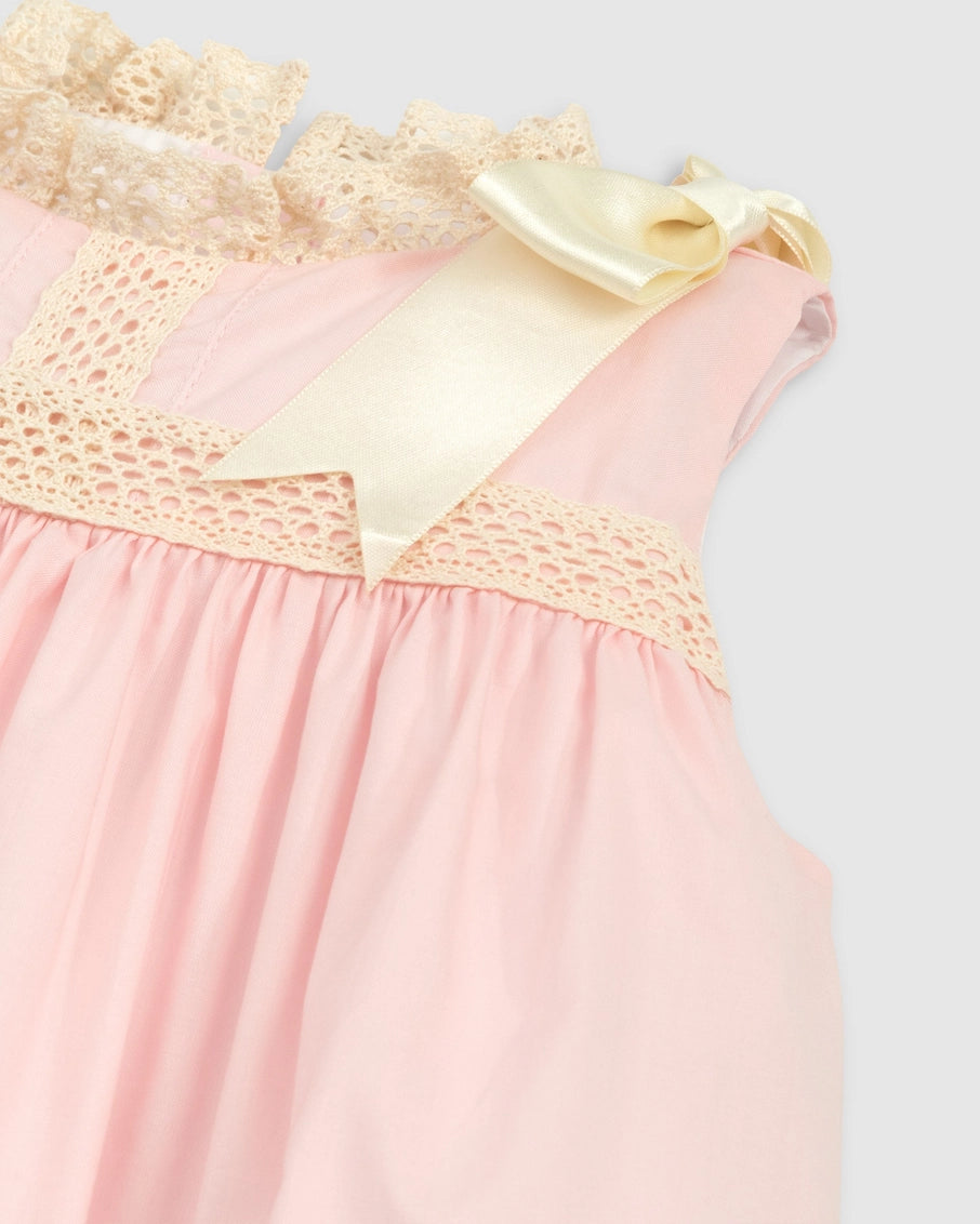 Close-up of a pink dress with lace details on a light gray background