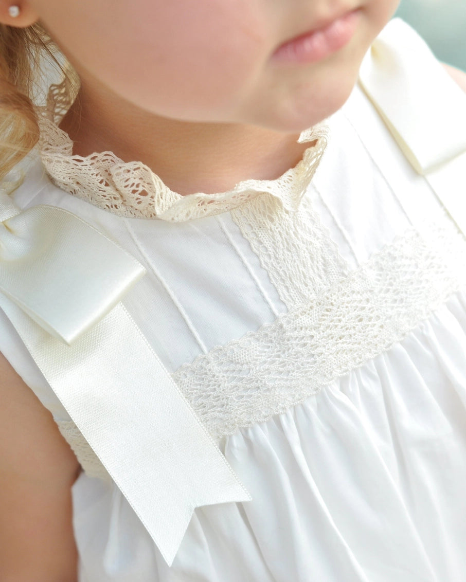Close-up of a child wearing a white dress with lace details