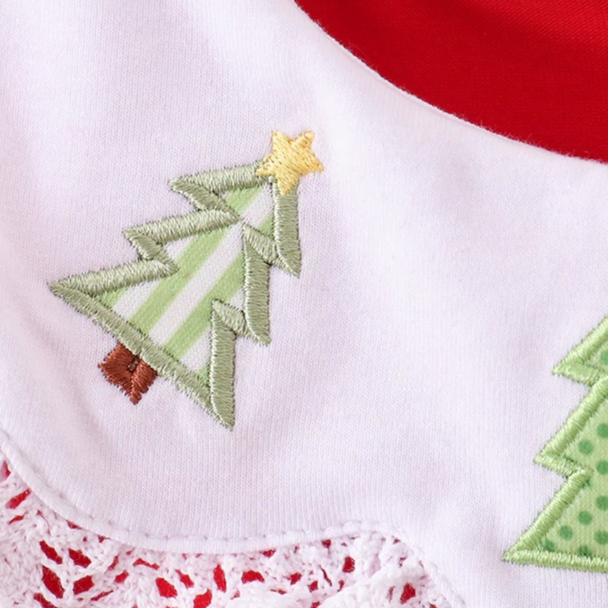 Embroidered Christmas tree design on a white fabric with red and green accents.