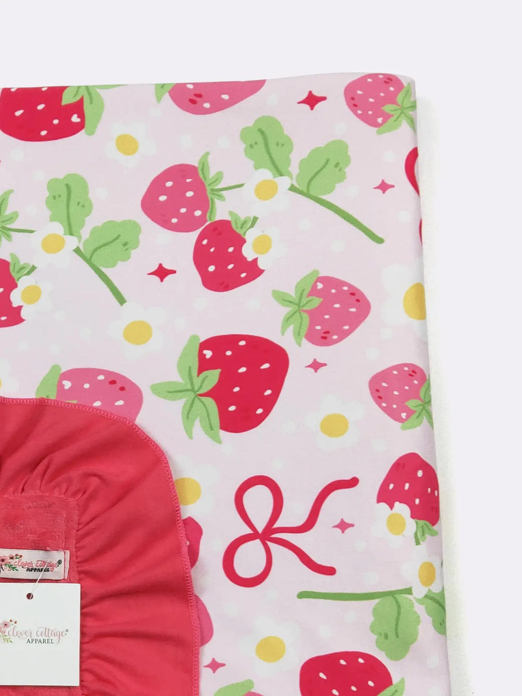 Fabric with strawberry pattern and red item partially visible