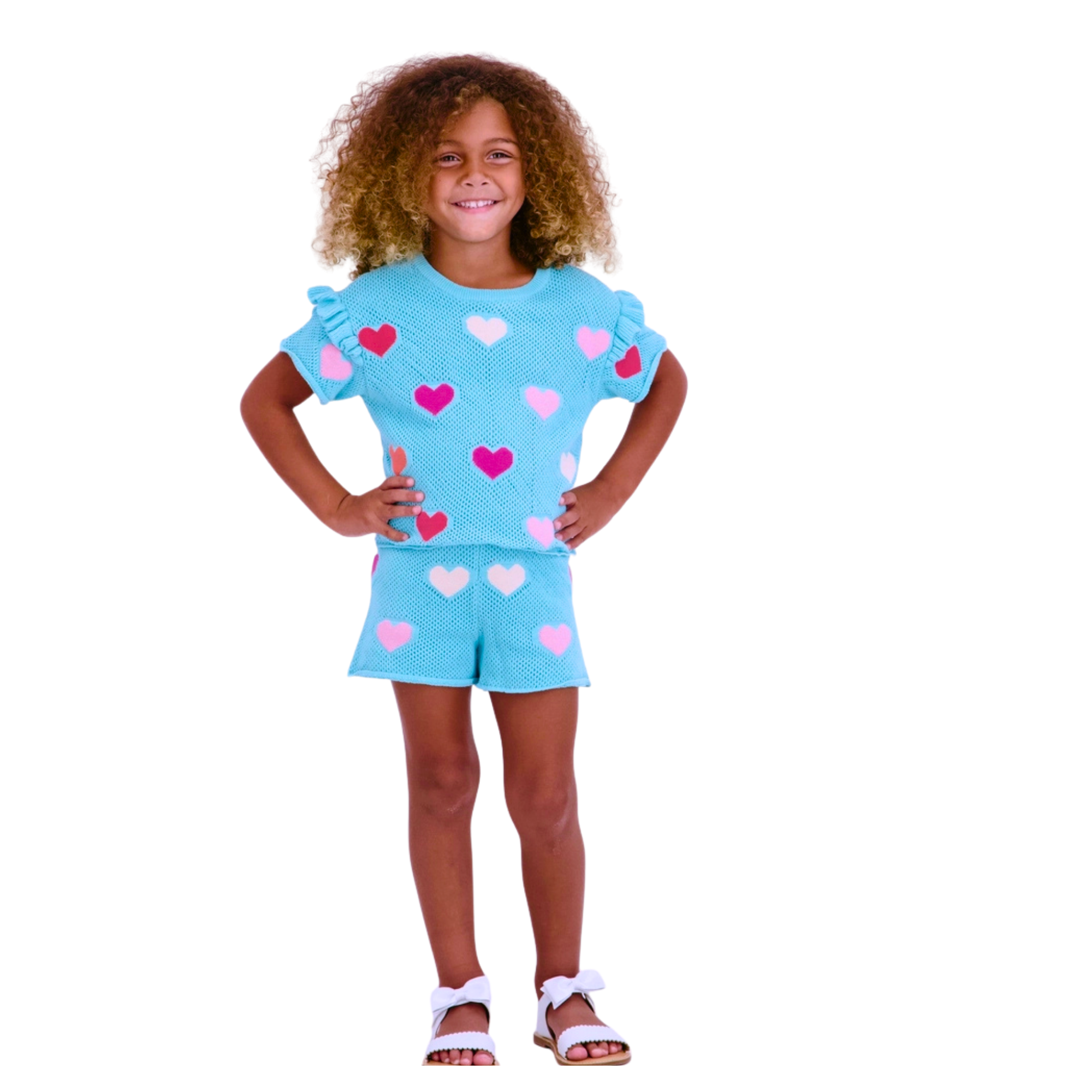Child wearing a light blue outfit with pink heart patterns on a white background