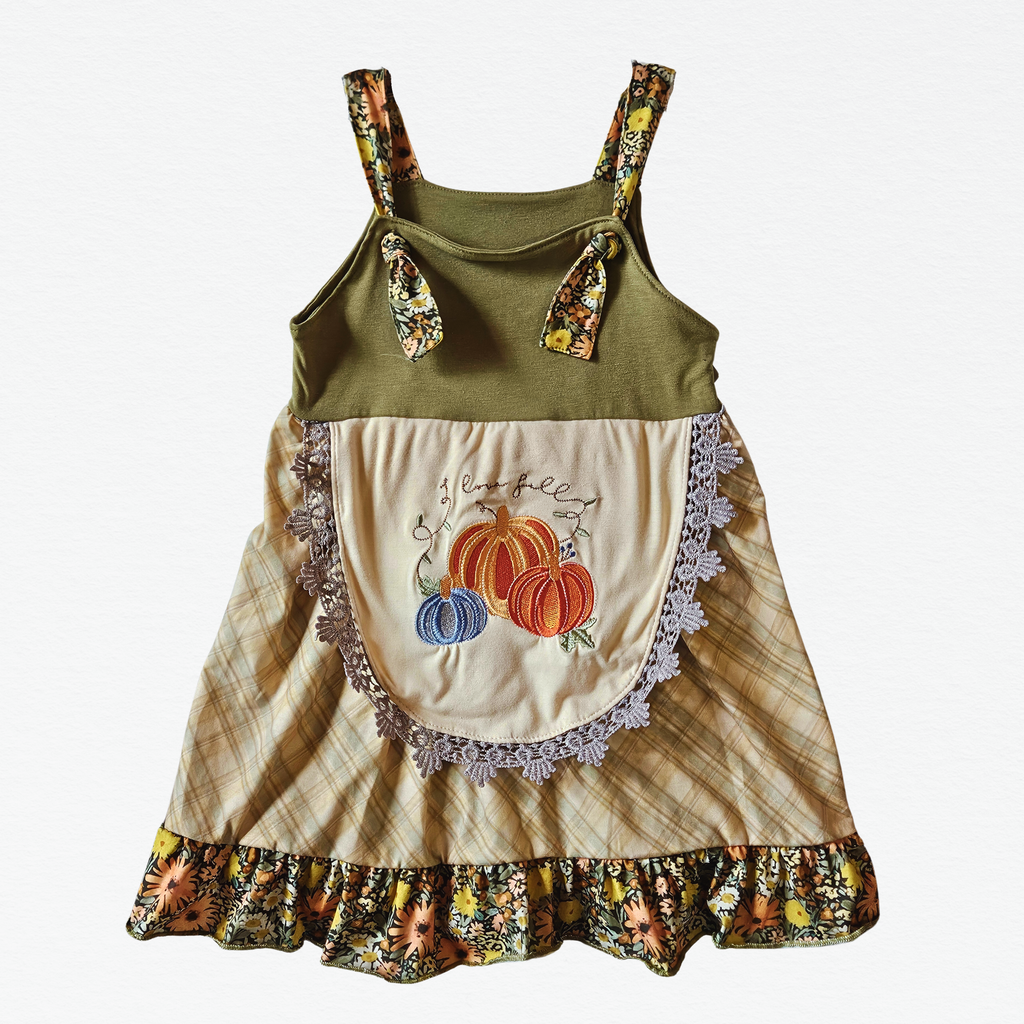 Children's dress with green top and floral straps, beige skirt with pumpkin design, on a white background.