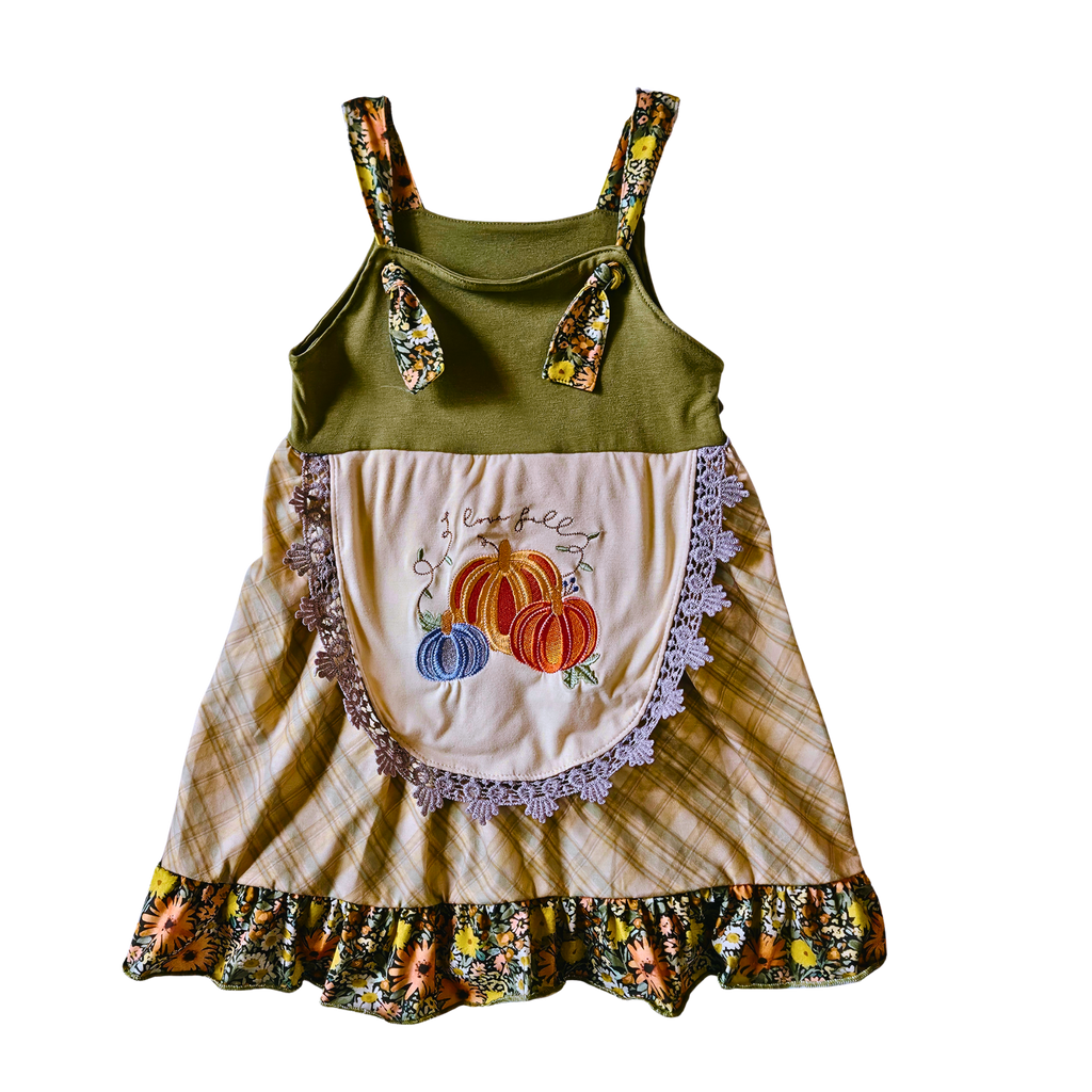 Children's dress with green top and floral straps, beige skirt with pumpkin design, on a white background.