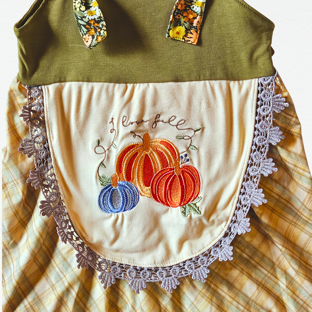 Embroidered apron with pumpkins and lace details on a plaid fabric background