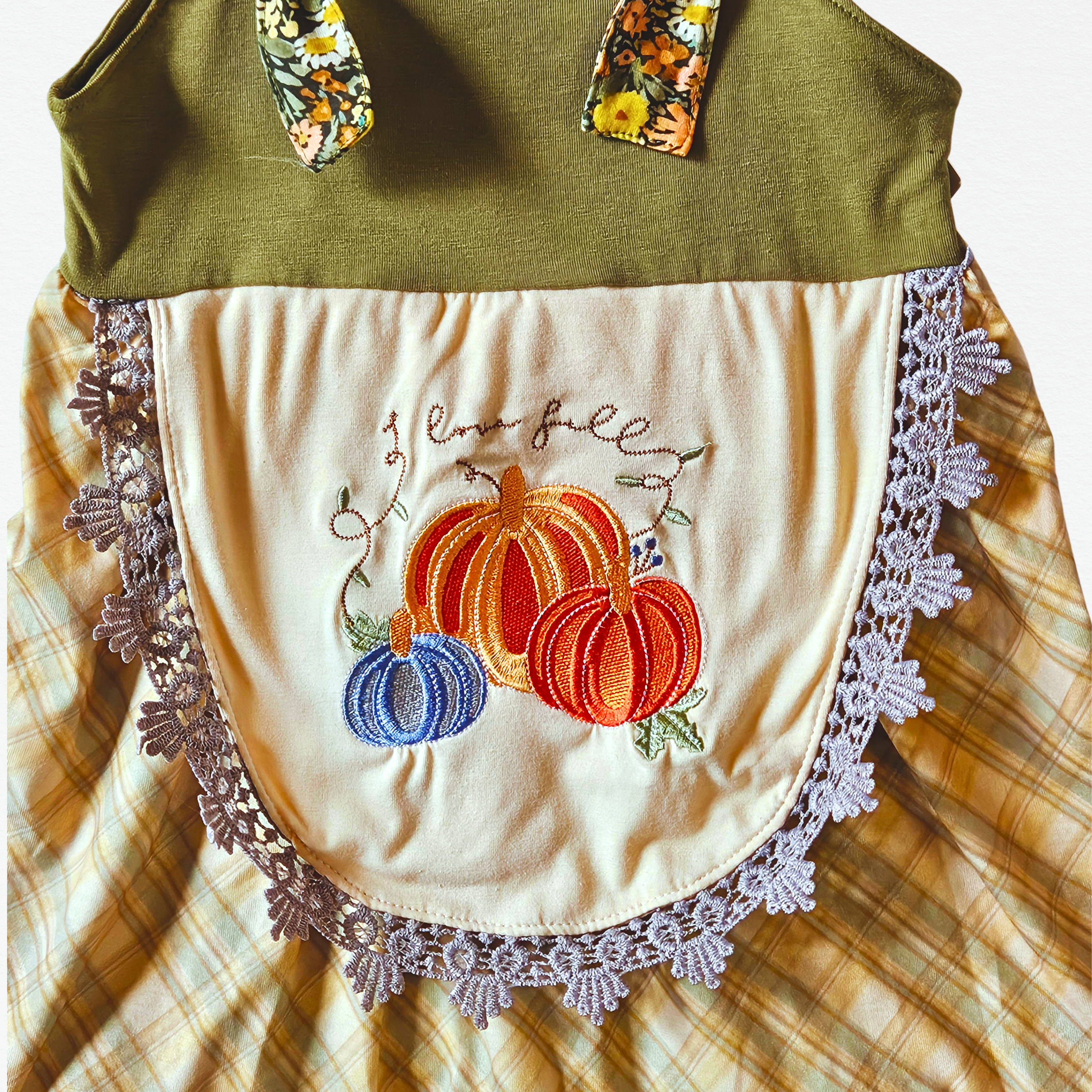 Embroidered apron with pumpkins and lace details on a plaid fabric background