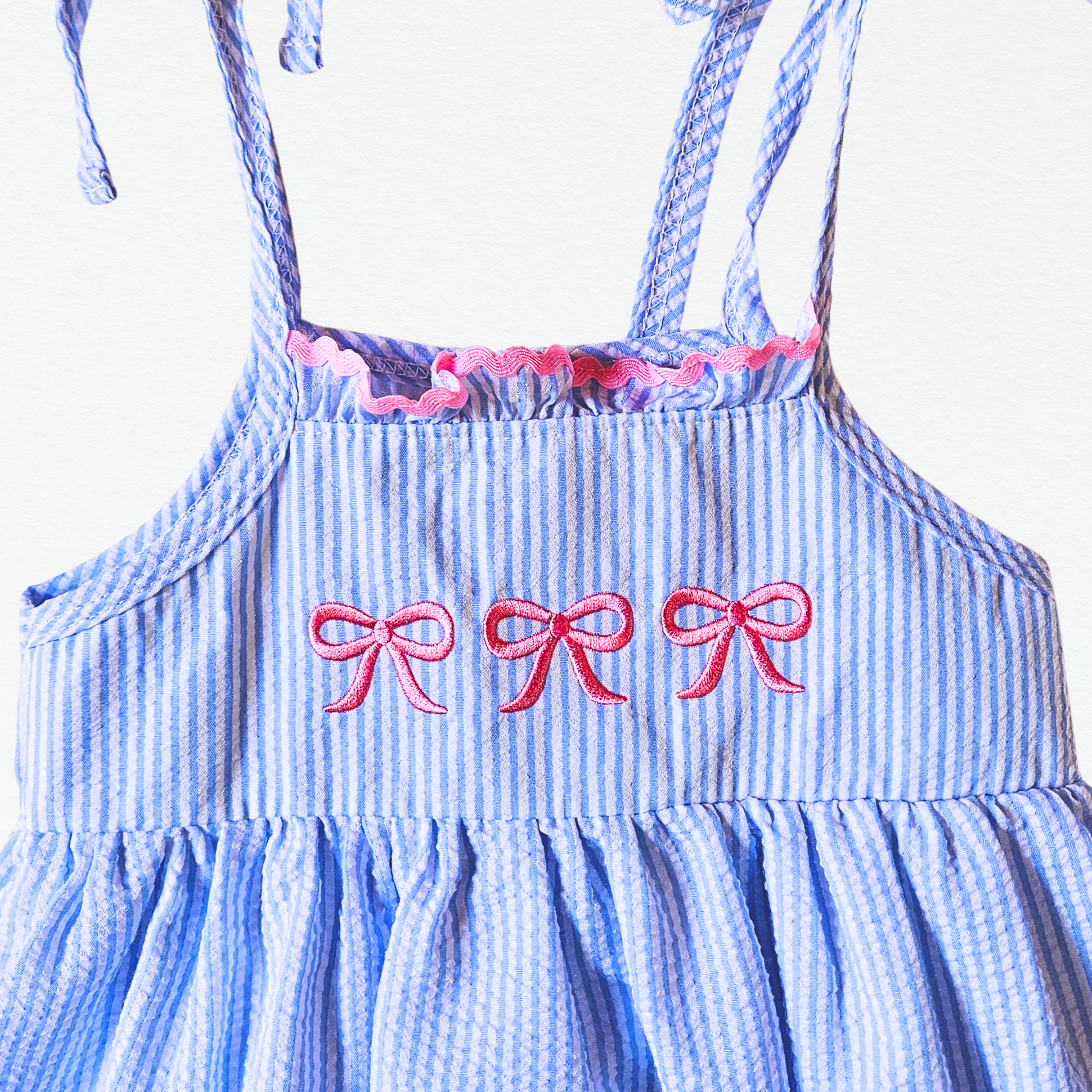 Blue and white striped dress with pink bows on a white background