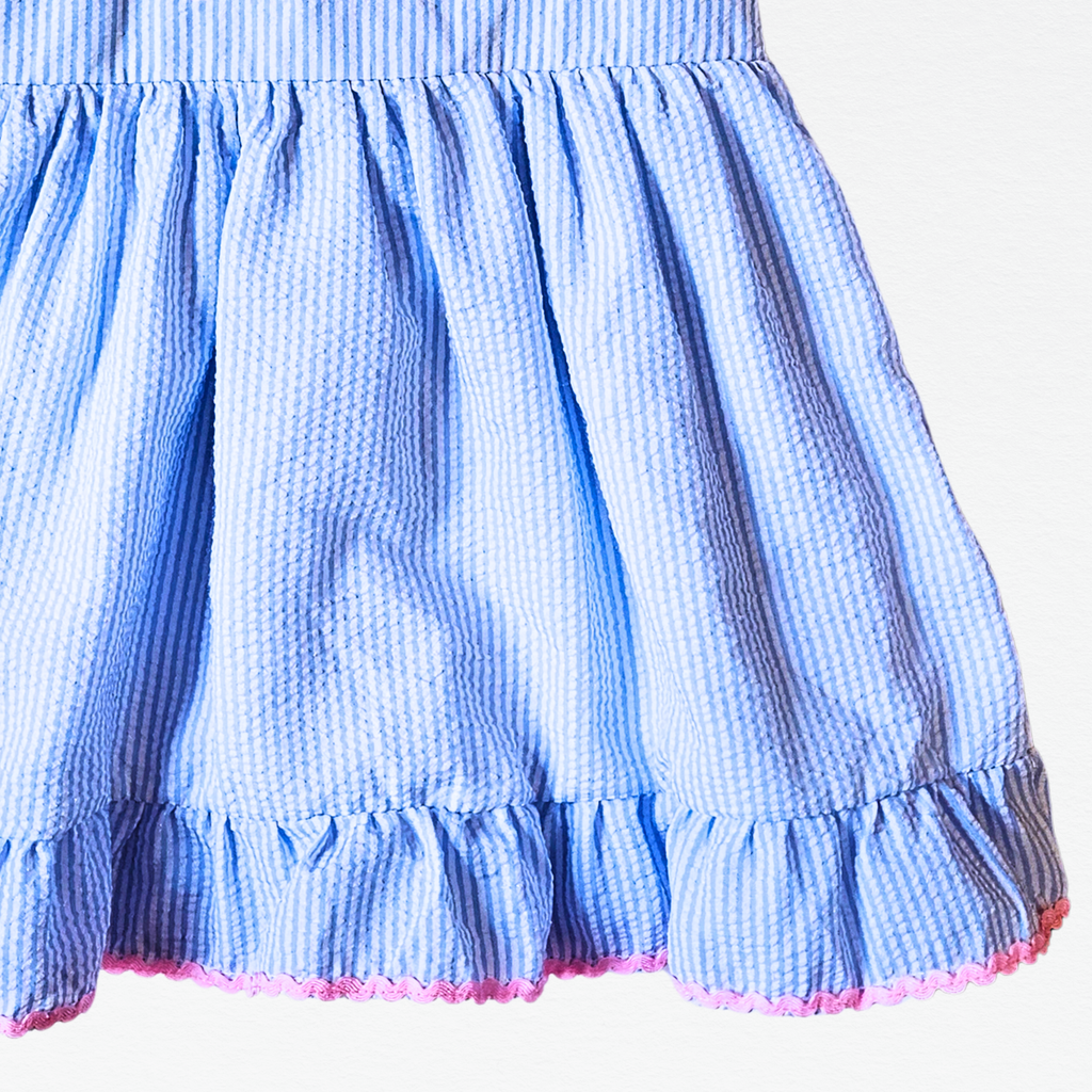 Close-up of a blue checkered dress with pink ruffled hem on a white background