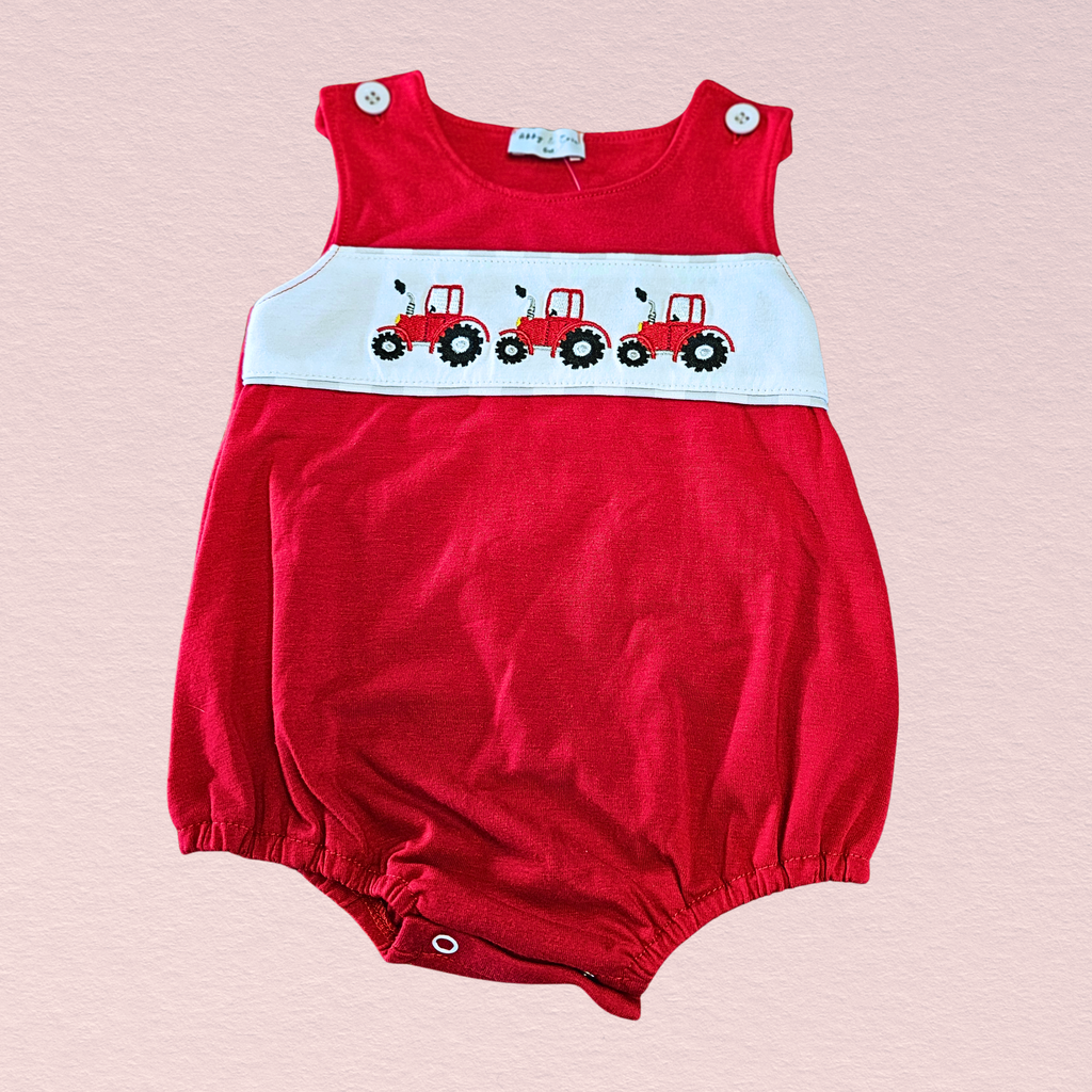 Red baby romper with tractor design on a pink background