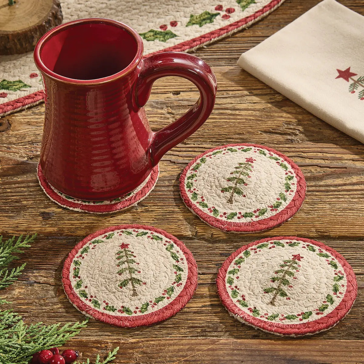Red mug on a wooden surface with Christmas-themed coasters