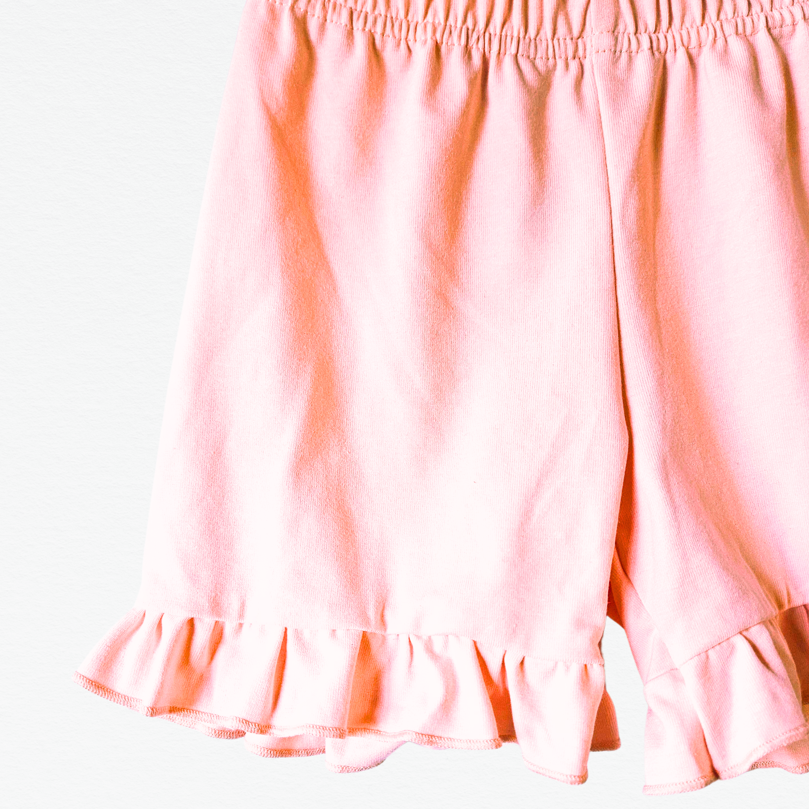 Pink shorts with ruffled hem on a white background
