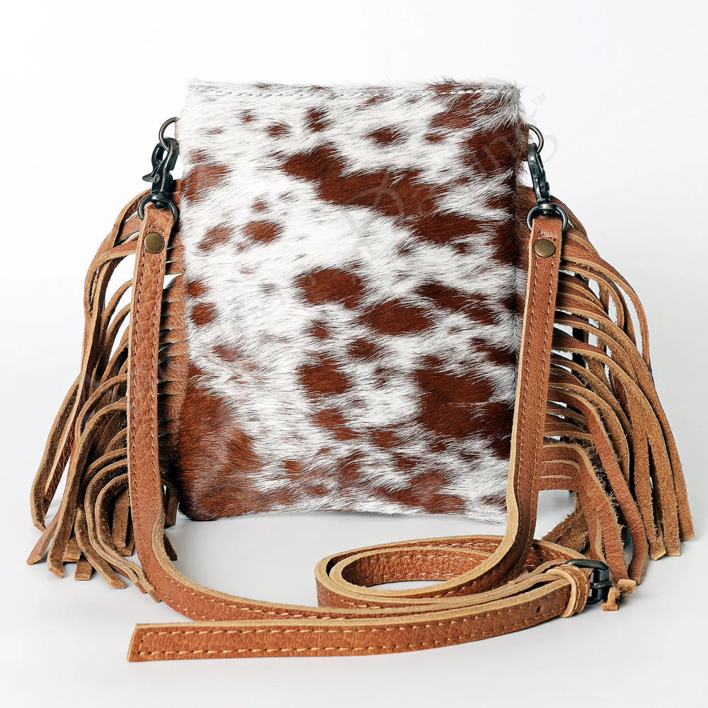 Brown and white cowhide leather bag with fringe on a white background