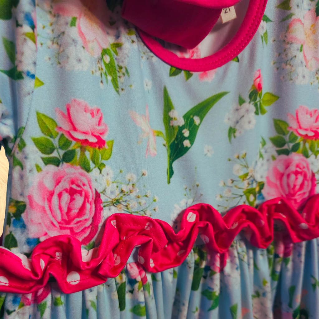Floral dress with pink roses and red ruffled trim, worn by a person.