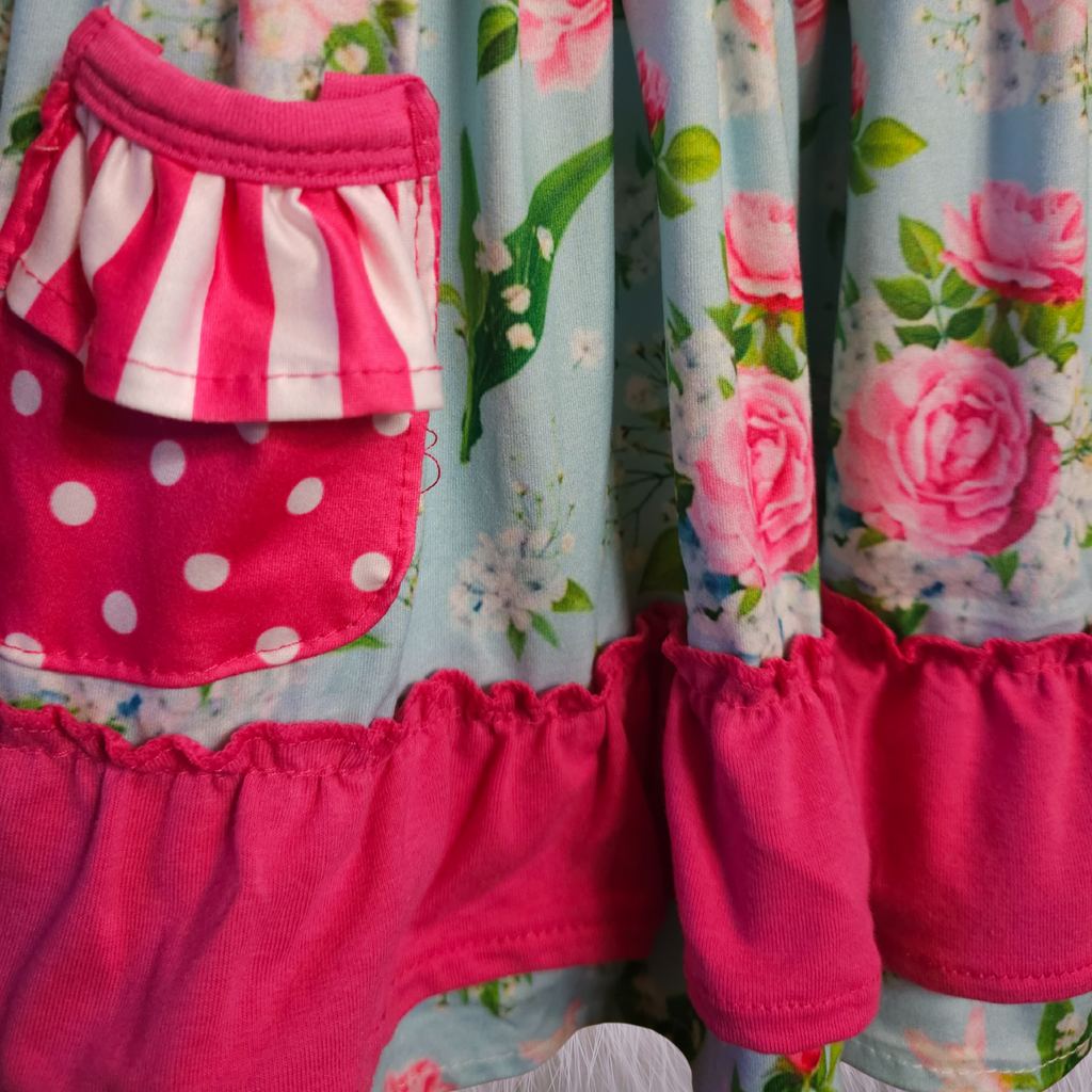 Close-up of a child's dress with floral and polka dot patterns.