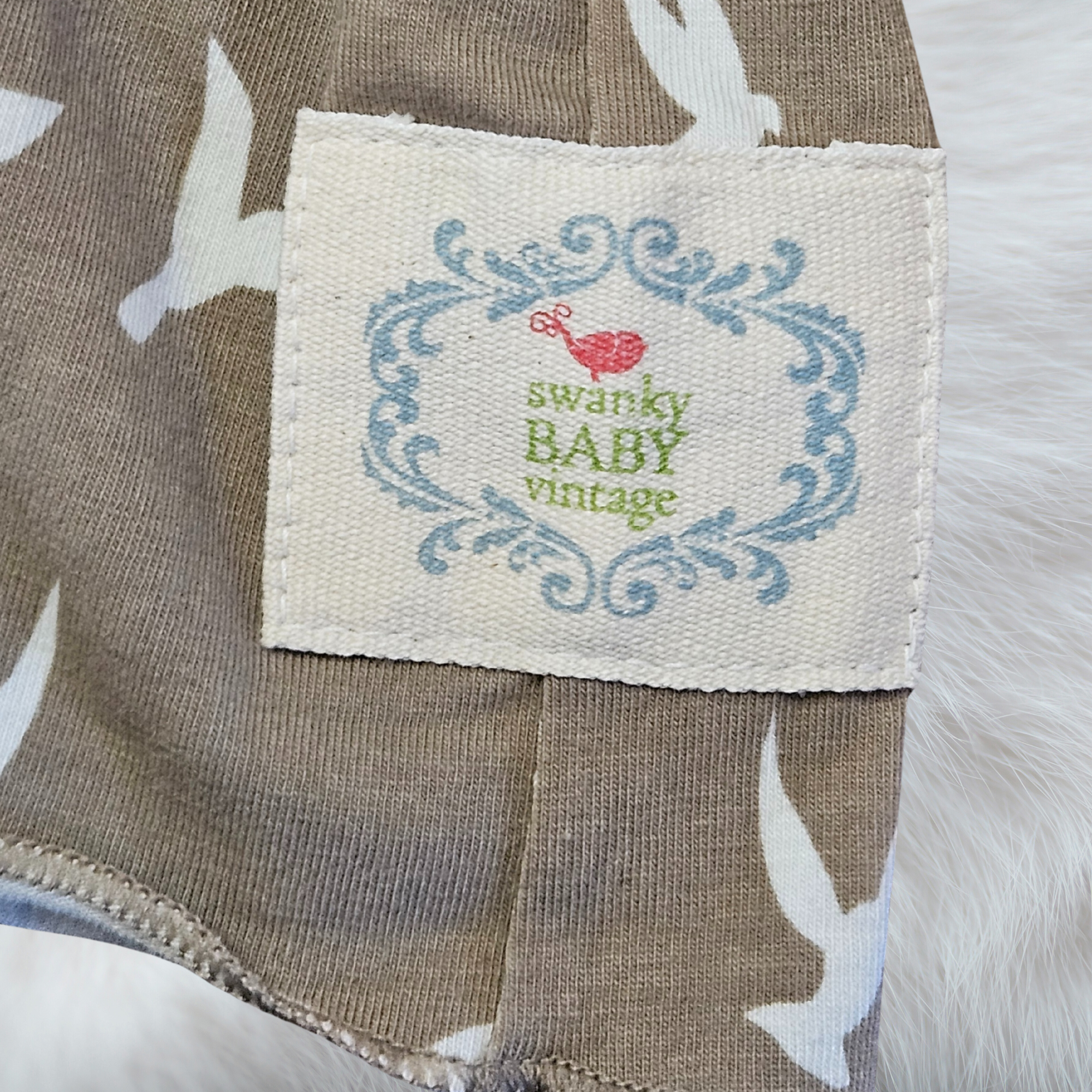 Fabric tag with 'swanky BABY vintage' text on a textured fabric background