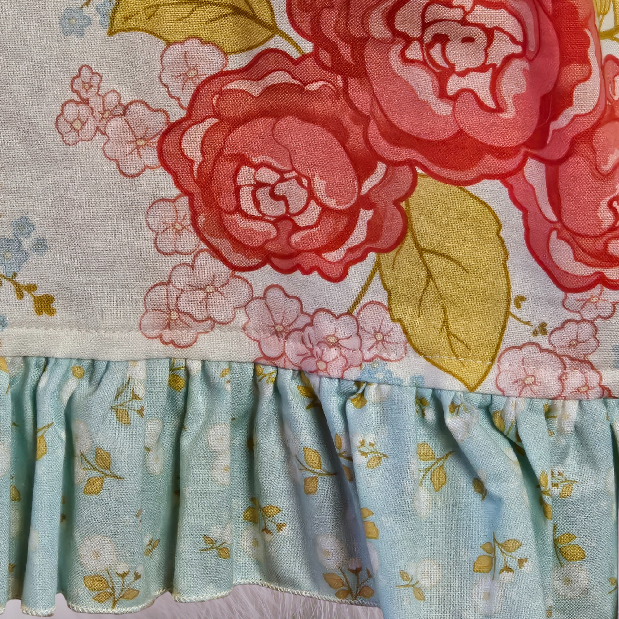 Floral fabric with red roses and light blue ruffled trim