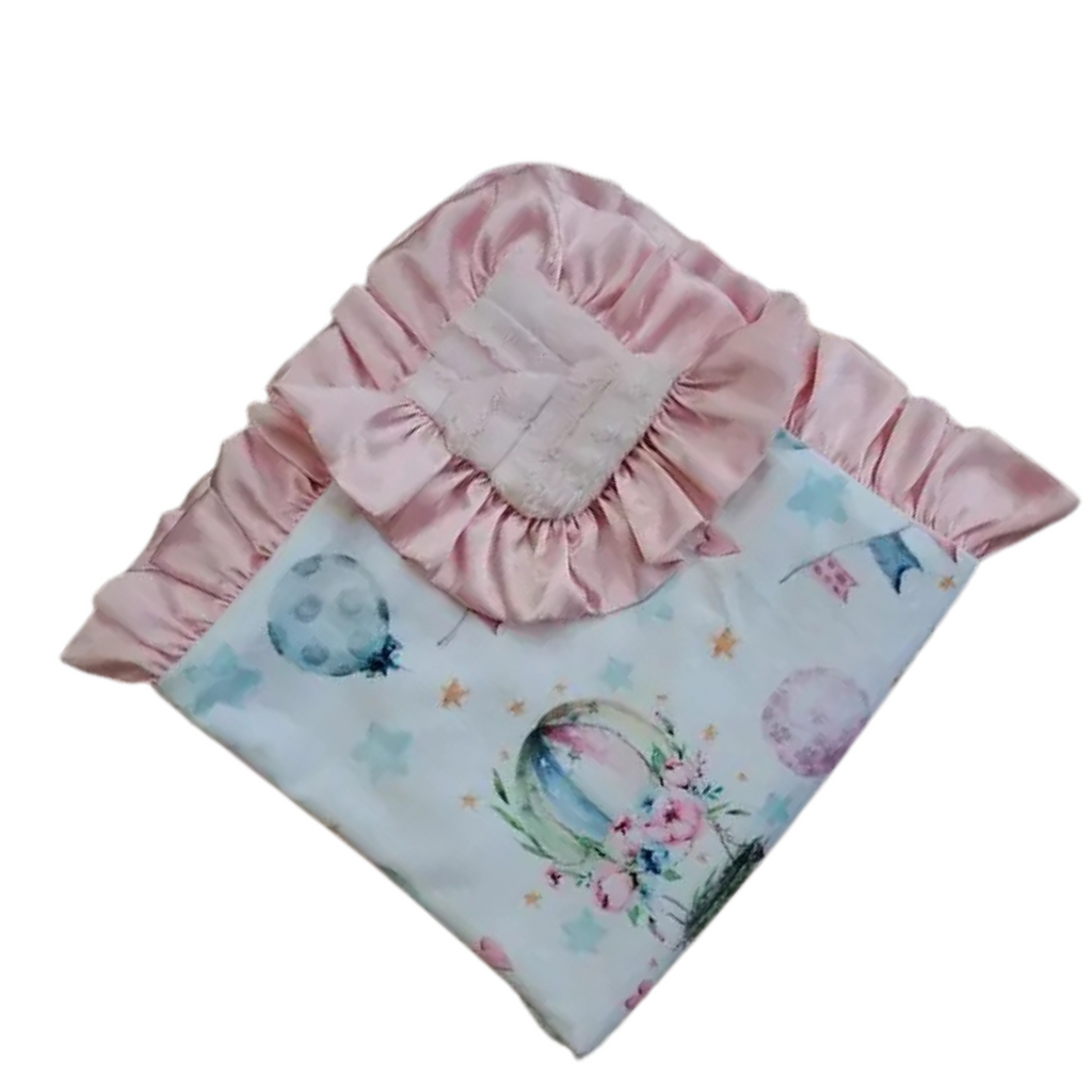 Baby hat and blanket set with pink ruffled trim on a white background