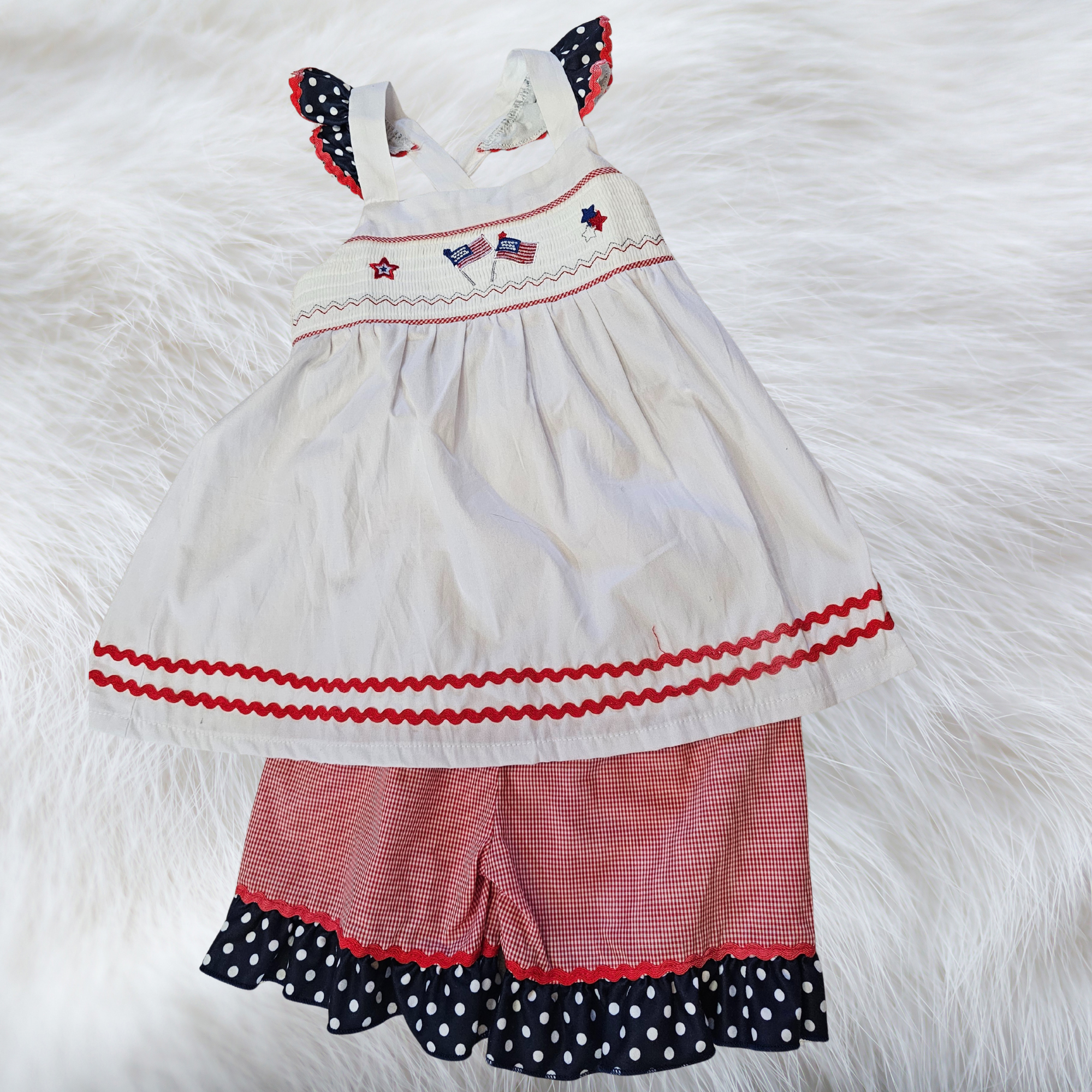 Children's dress with red, white, and blue accents on a fluffy white background