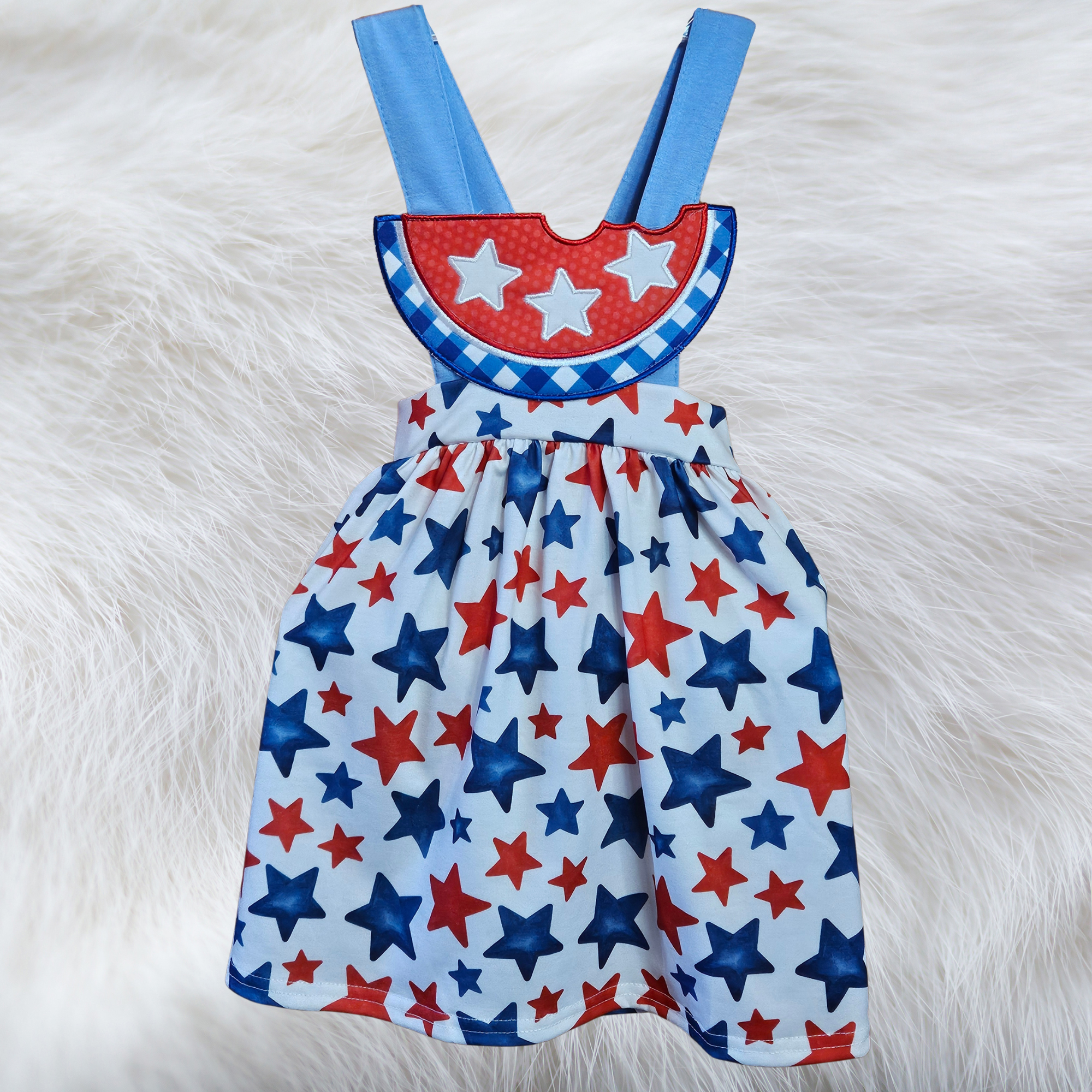 Children's dress with red, blue, and white star pattern on a fluffy white surface