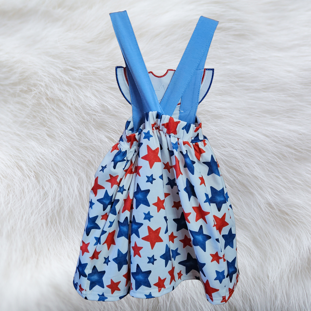 Children's dress with red, blue, and white star pattern on a fluffy white background