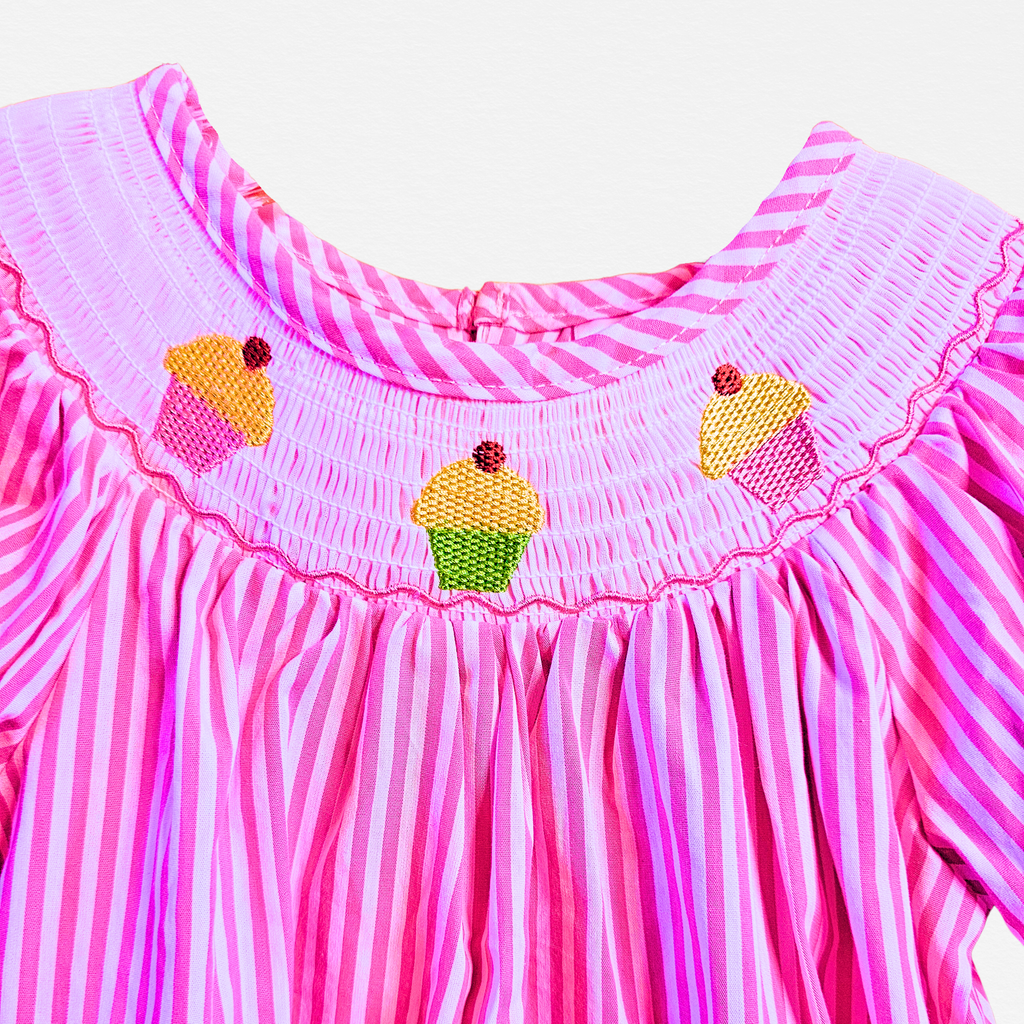 Pink and white striped dress with cupcake decorations on a white background