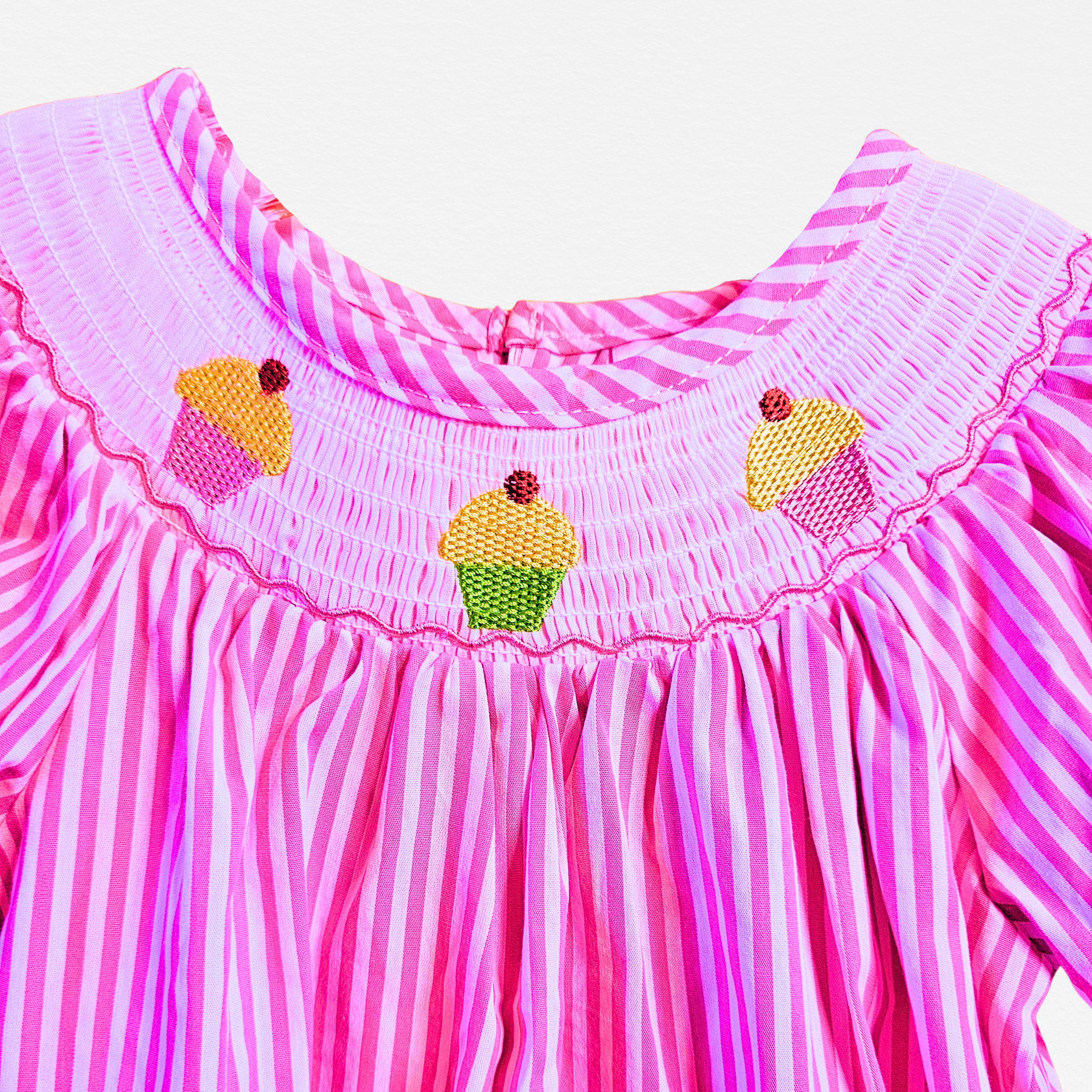 Pink and white striped dress with cupcake decorations on a white background