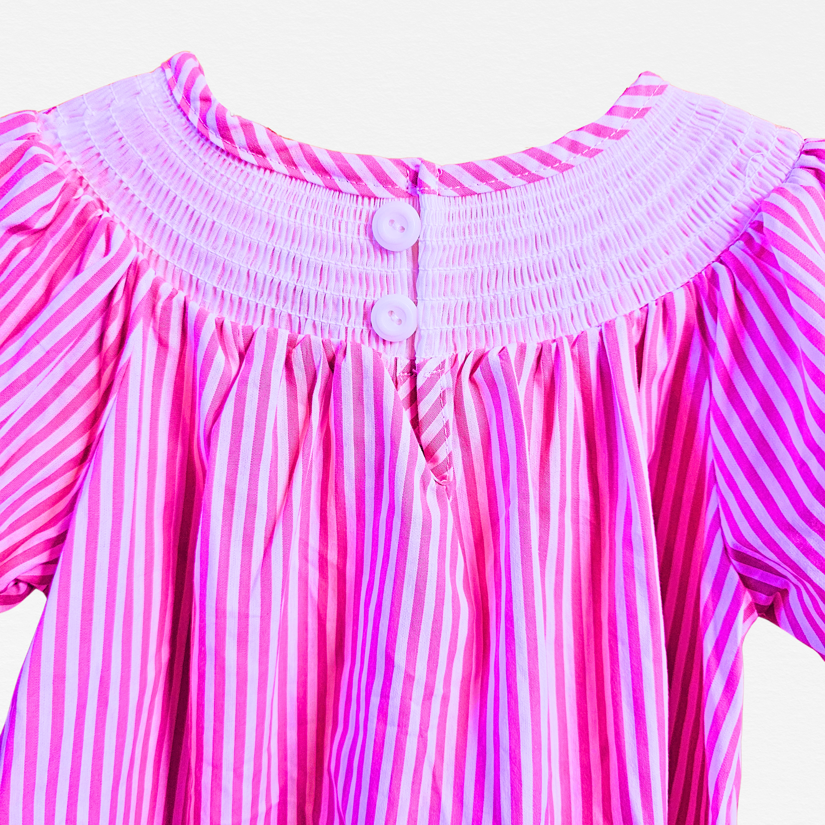 Close-up of a pink and white striped dress with a smocked neckline.