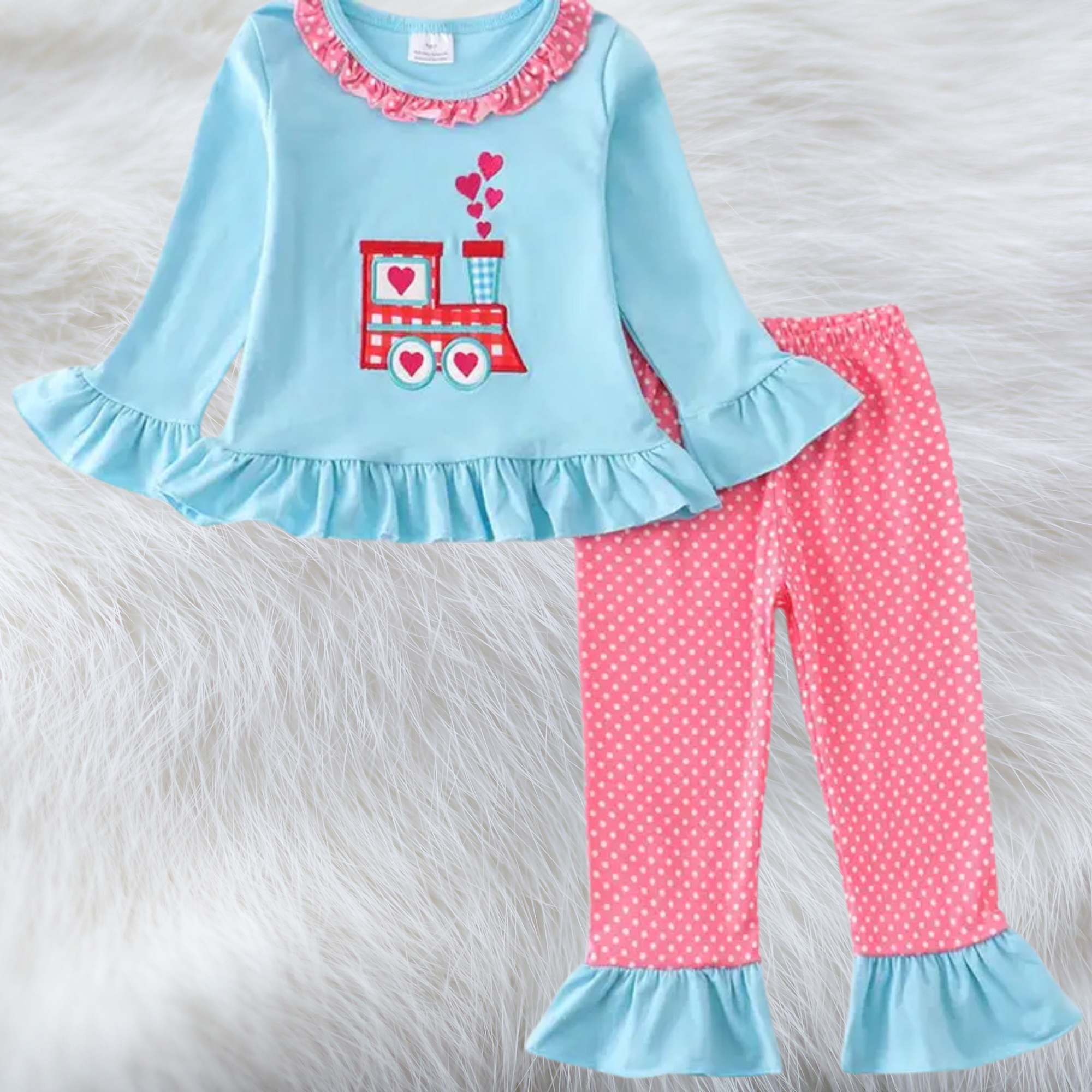 Children's outfit with blue top and pink pants on a fluffy white background