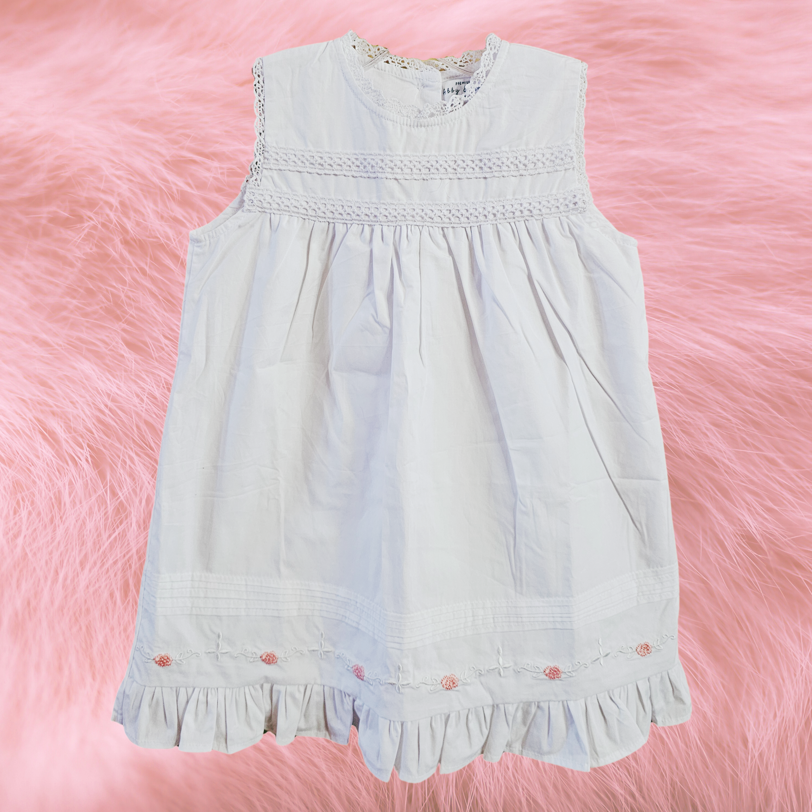 White dress with lace details on a pink fluffy background