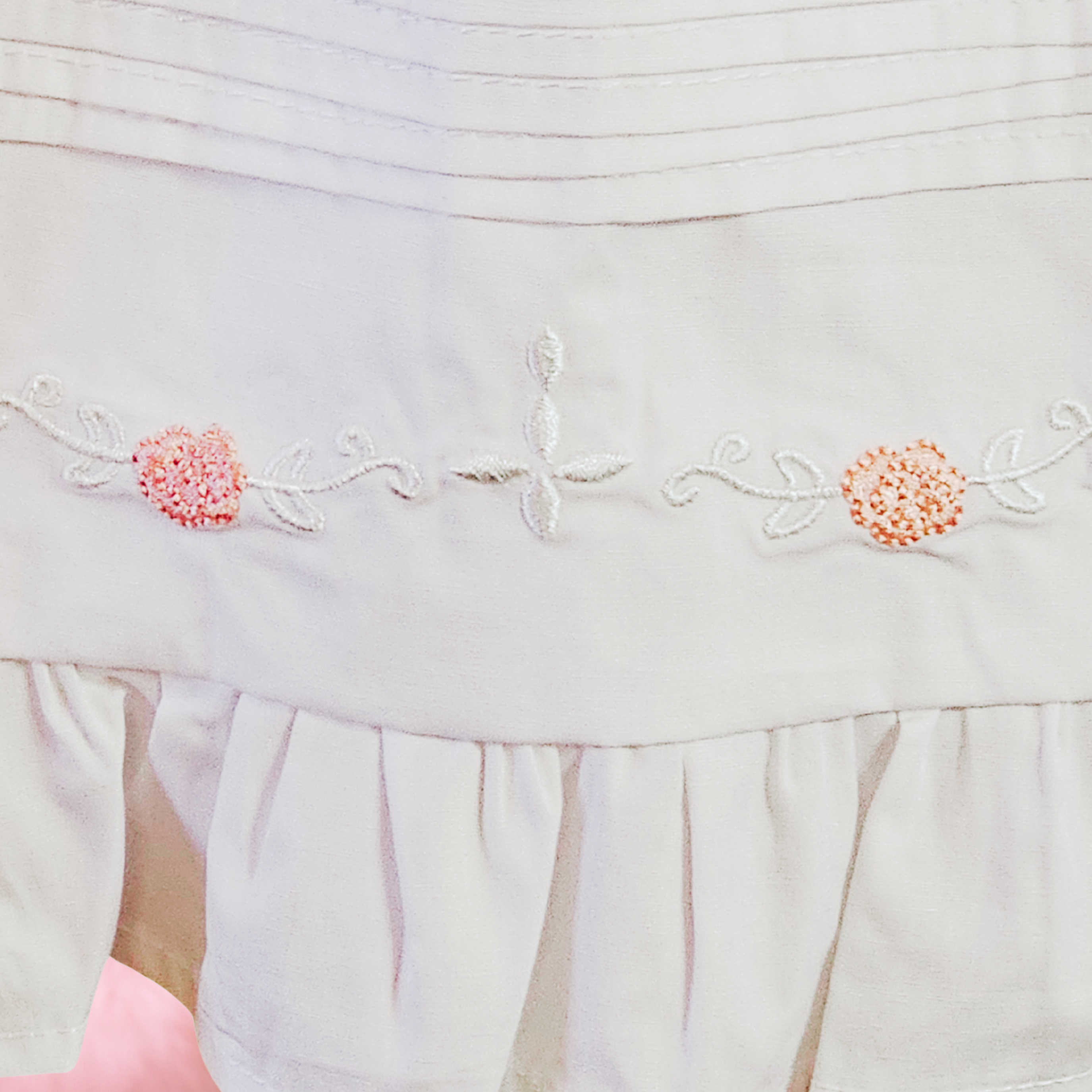 Light-colored fabric with floral embroidery and ruffled hem